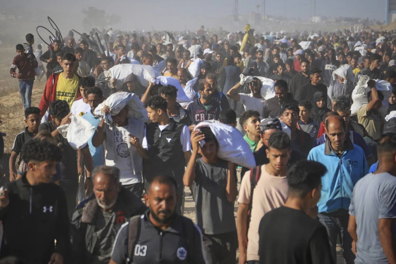 فلسطينيون يحملون صناديق بها مساعدات غذائية وأجولة طحين وزّعتها «مؤسسة غزة الإنسانية» في رفح جنوب قطاع غزة (أ.ب)