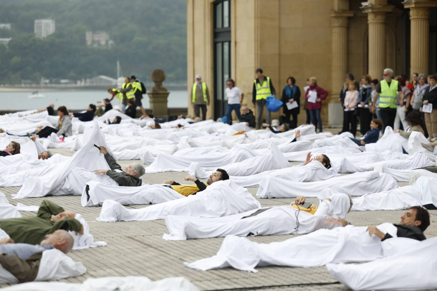 متظاهرون في إسبانيا يلفّون أنفسهم بأكفان بيضاء تضامناً مع ضحايا غزة يوم الأحد (إ.ب.أ)