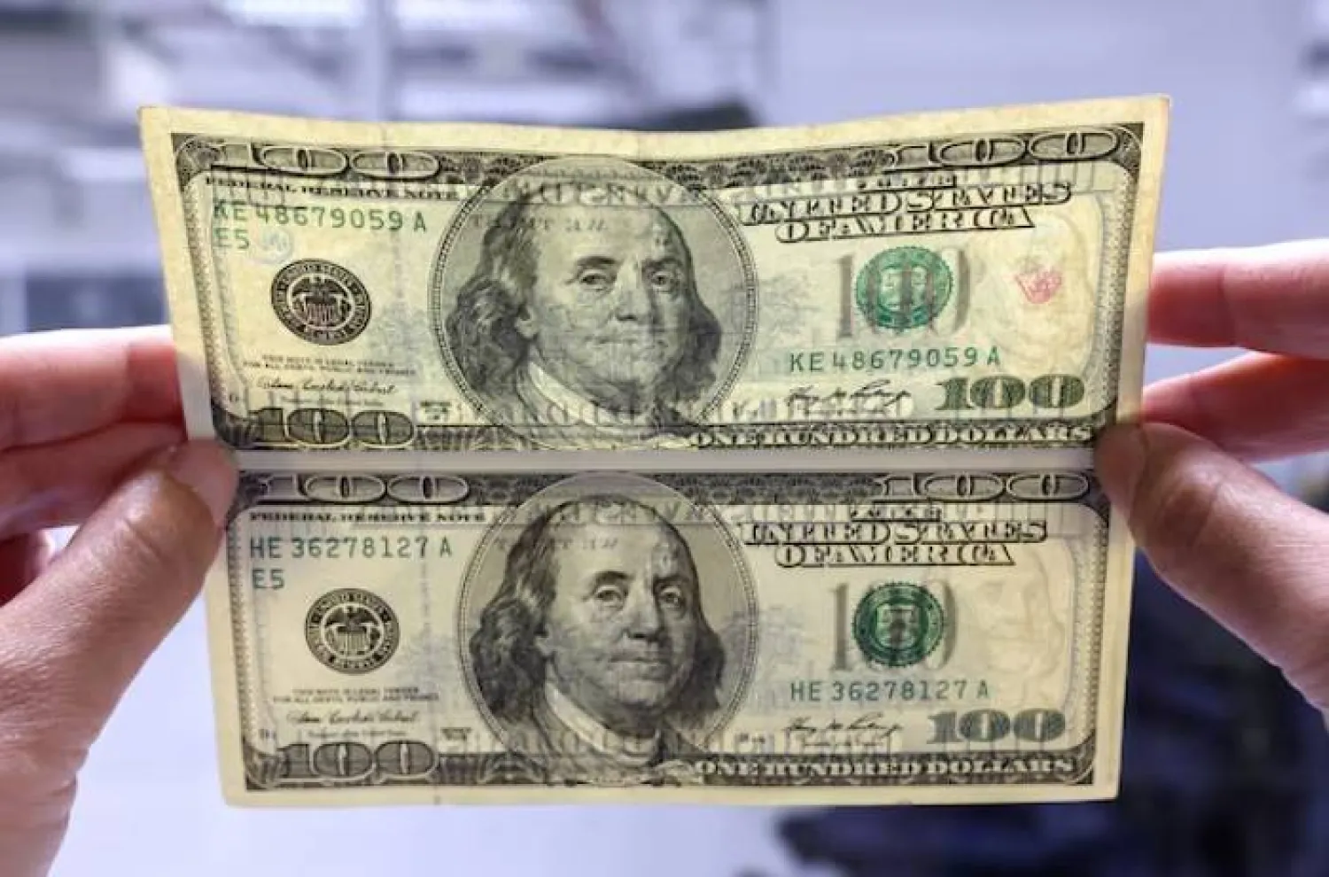 موظف بنك في بانكوك يقارن بين ورقة دولار مزيفة وأخرى أصلية (أرشيفية - رويترز)