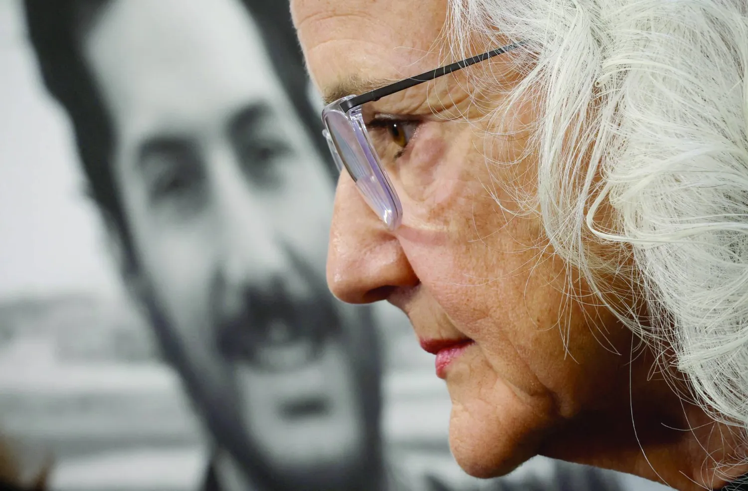 ديبرا تايس أمام صورة لابنها أوستن في واشنطن 2023 الذي اختُطف أثناء تغطيته الأحداث بسوريا عام 2012 (رويترز)