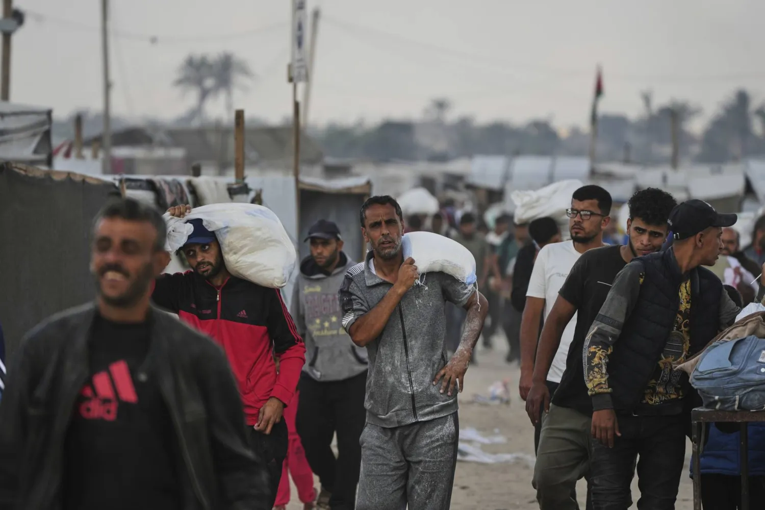 فلسطينيون يحملون أكياساً مليئة بالطعام والمساعدات الإنسانية المقدمة من «مؤسسة غزة الإنسانية» في خان يونس اليوم (أ.ب)