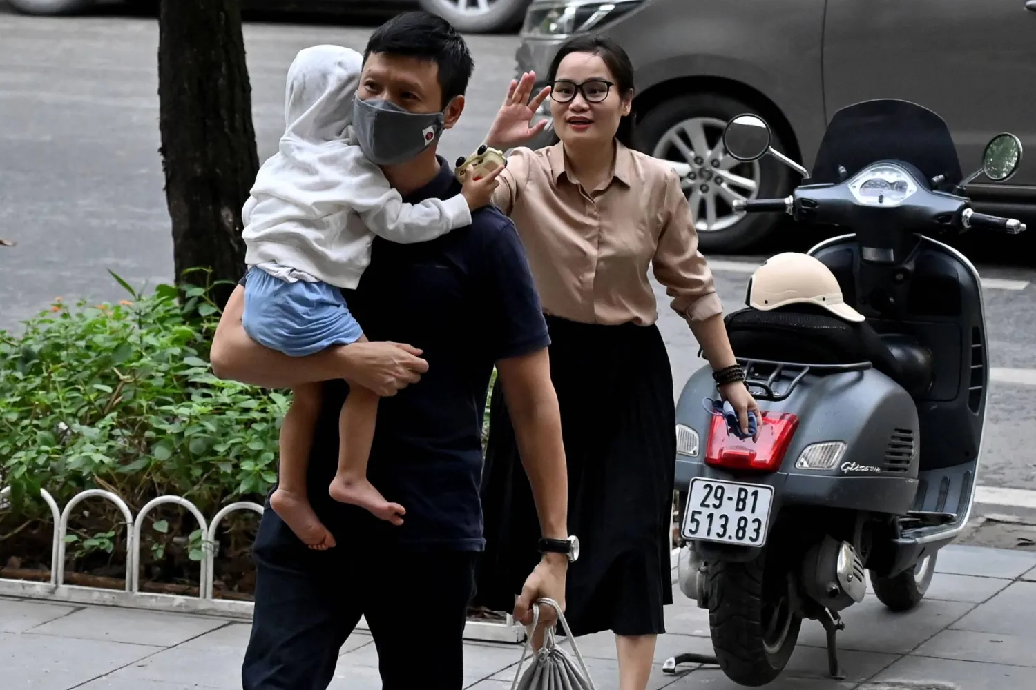 أم فيتنامية تلوح لابنتها لدى بوابة حضانة في هانوي العاصمة (أ.ف.ب)