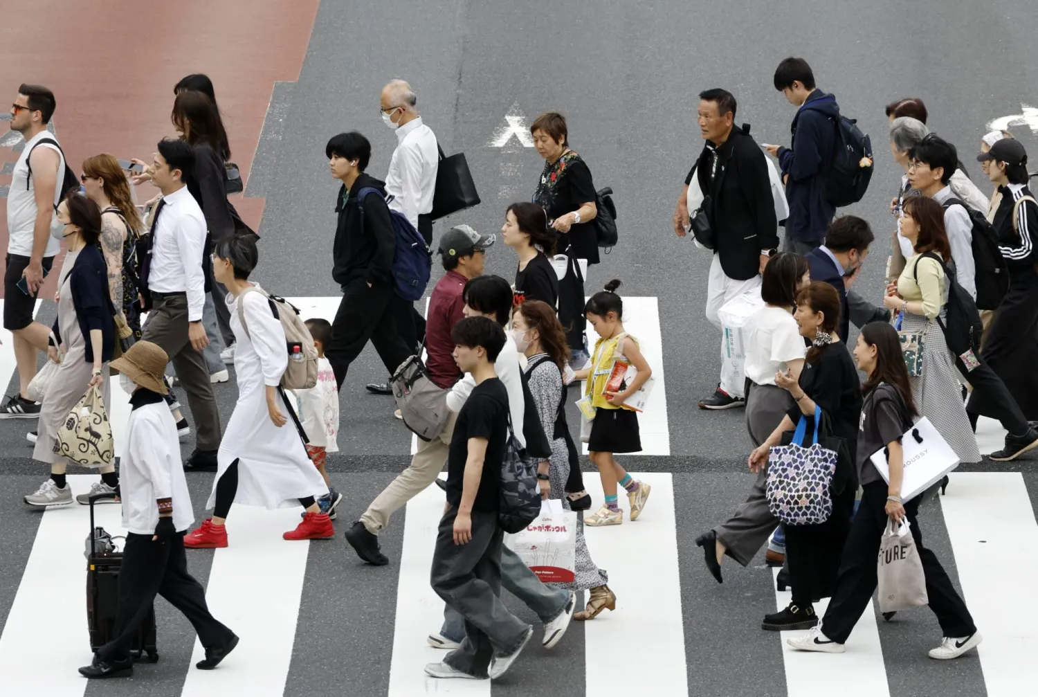 مشاة يعبرون الشارع في الضاحية المالية بوسط العاصمة اليابانية طوكيو (إ.ب.أ)