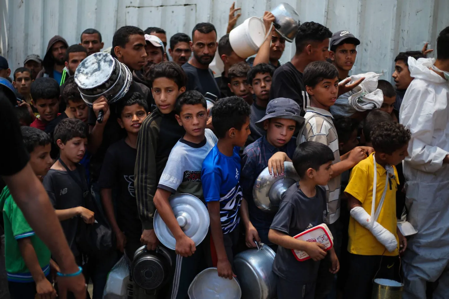 أطفال فلسطينيون ينتظرون للحصول على الطعام عند نقطة توزيع في مخيم النصيرات وسط قطاع غزة (أ.ف.ب)