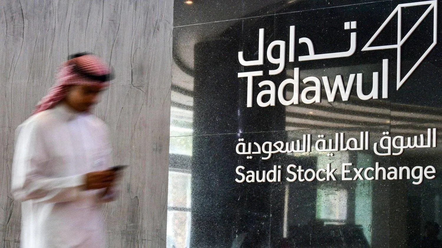 رجل يسير بالقرب من قاعة التداول بالسوق المالية السعودية في الرياض (أ.ف.ب)
