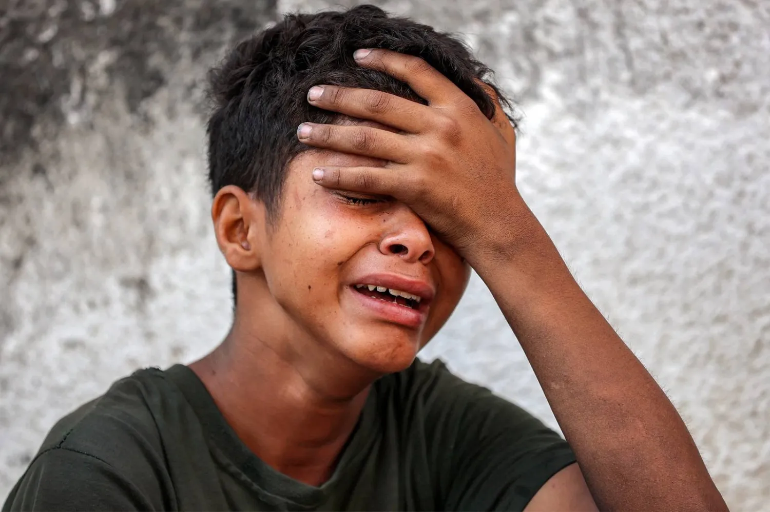 طفل فلسطيني يبكي خلال جنازة ضحايا القصف الإسرائيلي الليلي على مستشفى الشفاء بمدينة غزة (أ.ف.ب)