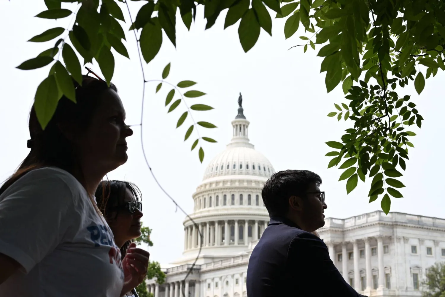 يستمع الناس إلى متظاهرين يتجمعون للتظاهر قبل مؤتمر صحافي لدعوة أعضاء مجلس الشيوخ الجمهوريين للتصويت ضد الموازنة (أ.ف.ب)