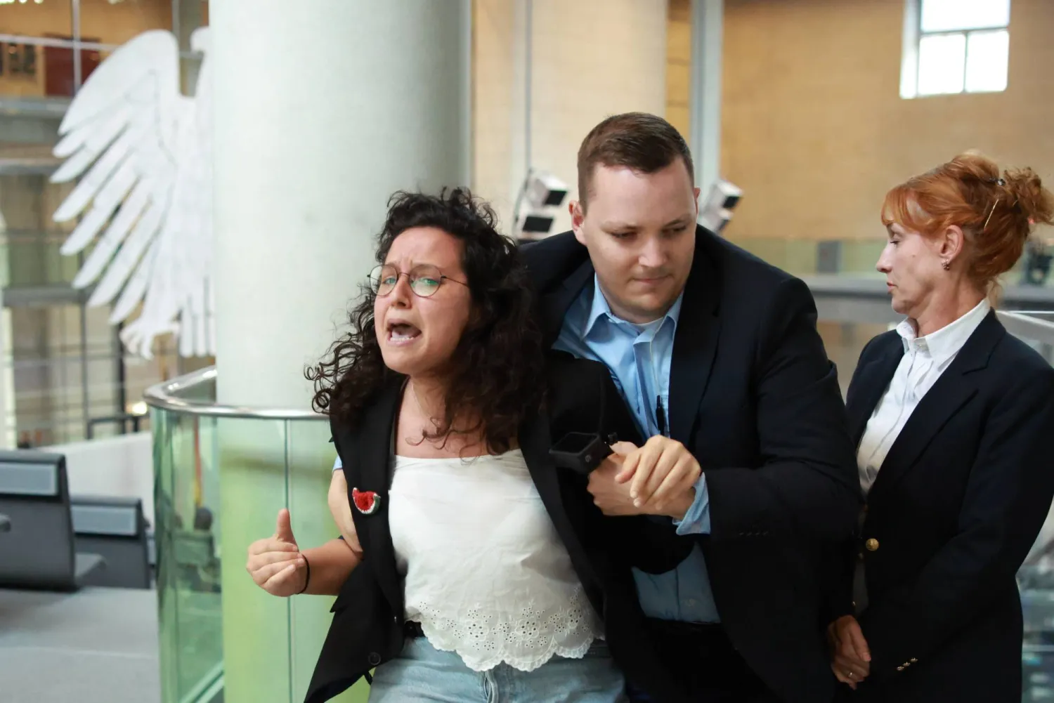 إخراج امرأة من شرفة الزوار بعد أن قاطعت جلسة استجواب الحكومة الألمانية (إ.ب.أ) 