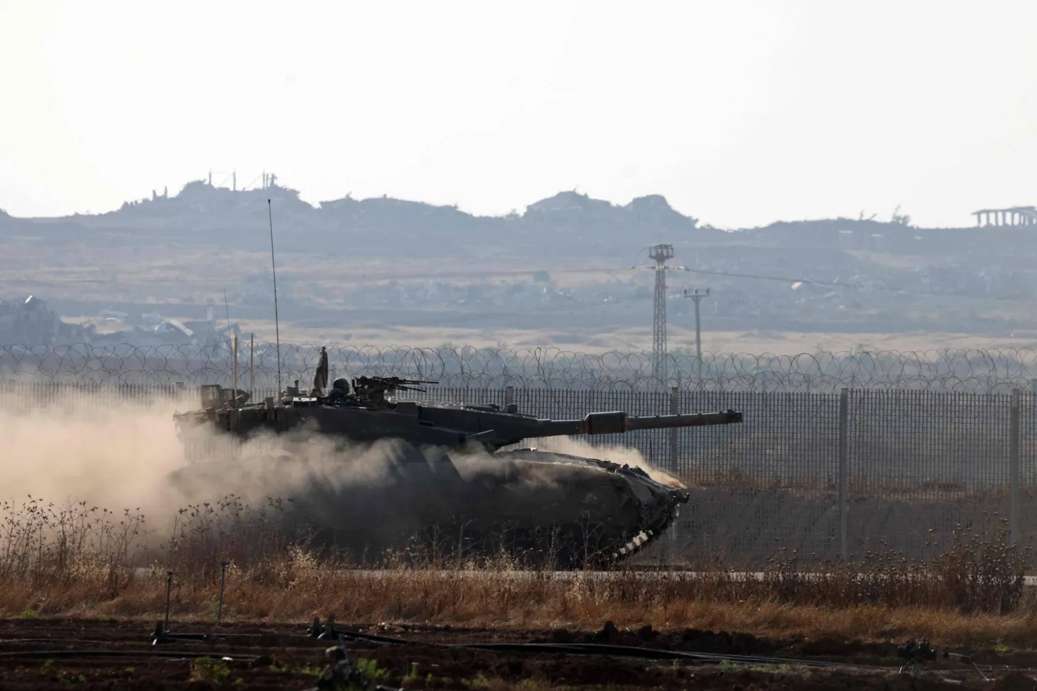 صورة التقطت من حدود إسرائيل مع قطاع غزة تظهر دبابة إسرائيلية تتجول على طول السياج الحدودي (أ.ف.ب)