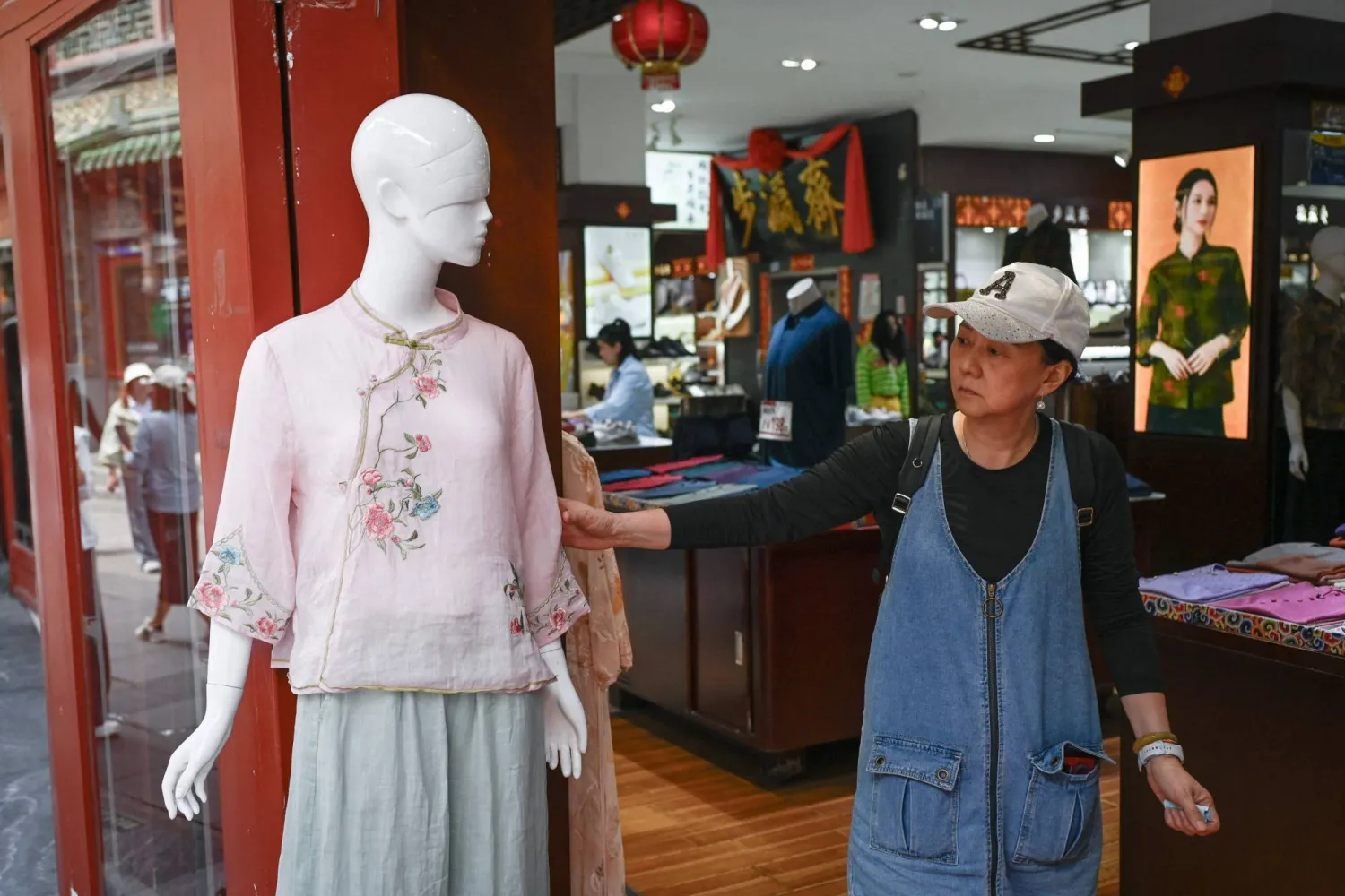 سيدة تفحص قطعة ملابس في أحد المتاجر بالعاصمة الصينية بكين (أ.ف.ب)