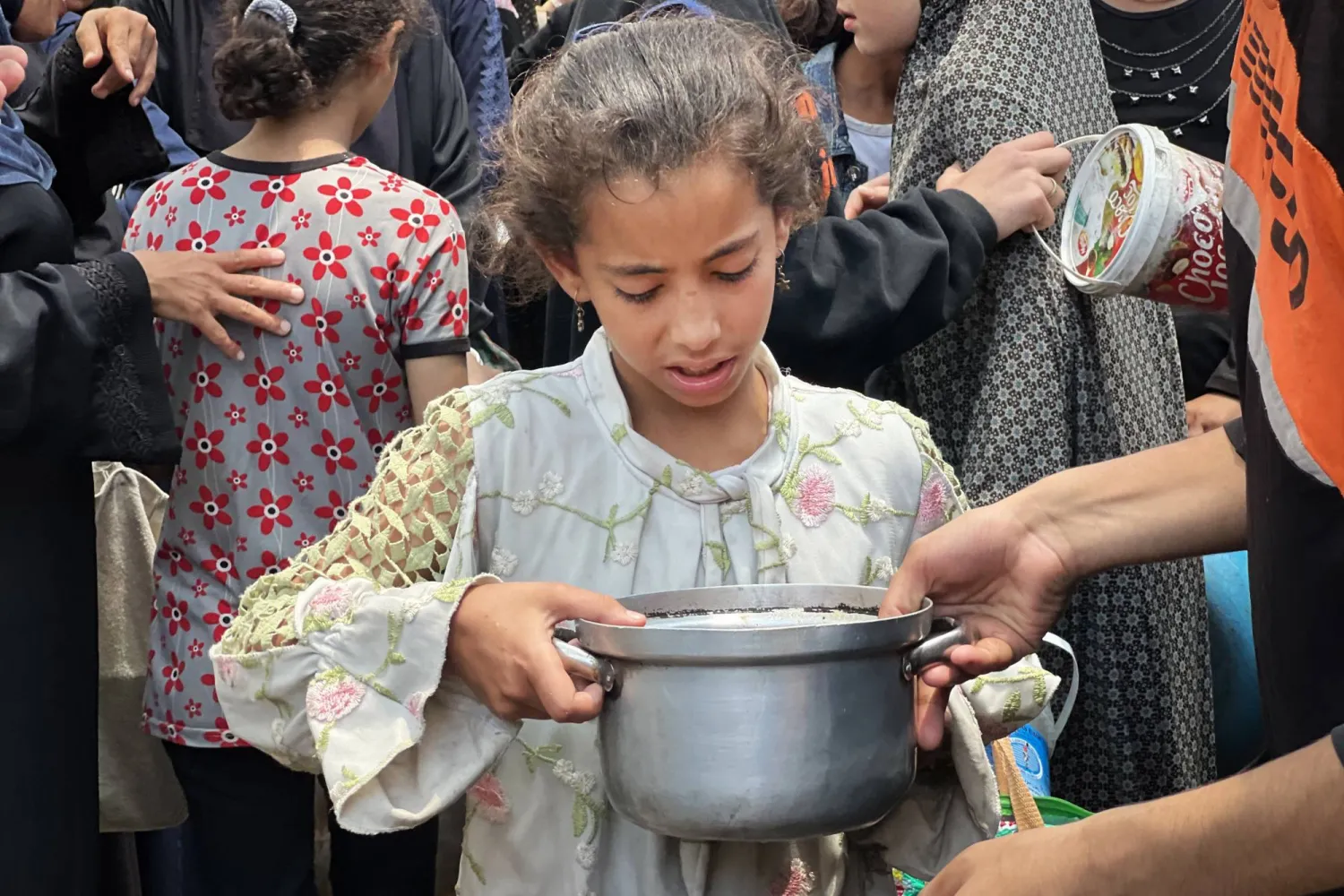 نازحون فلسطينيون يتلقون المساعدات وسط نقص الغذاء بمخيم النصيرات للاجئين في غزة (د.ب.أ)