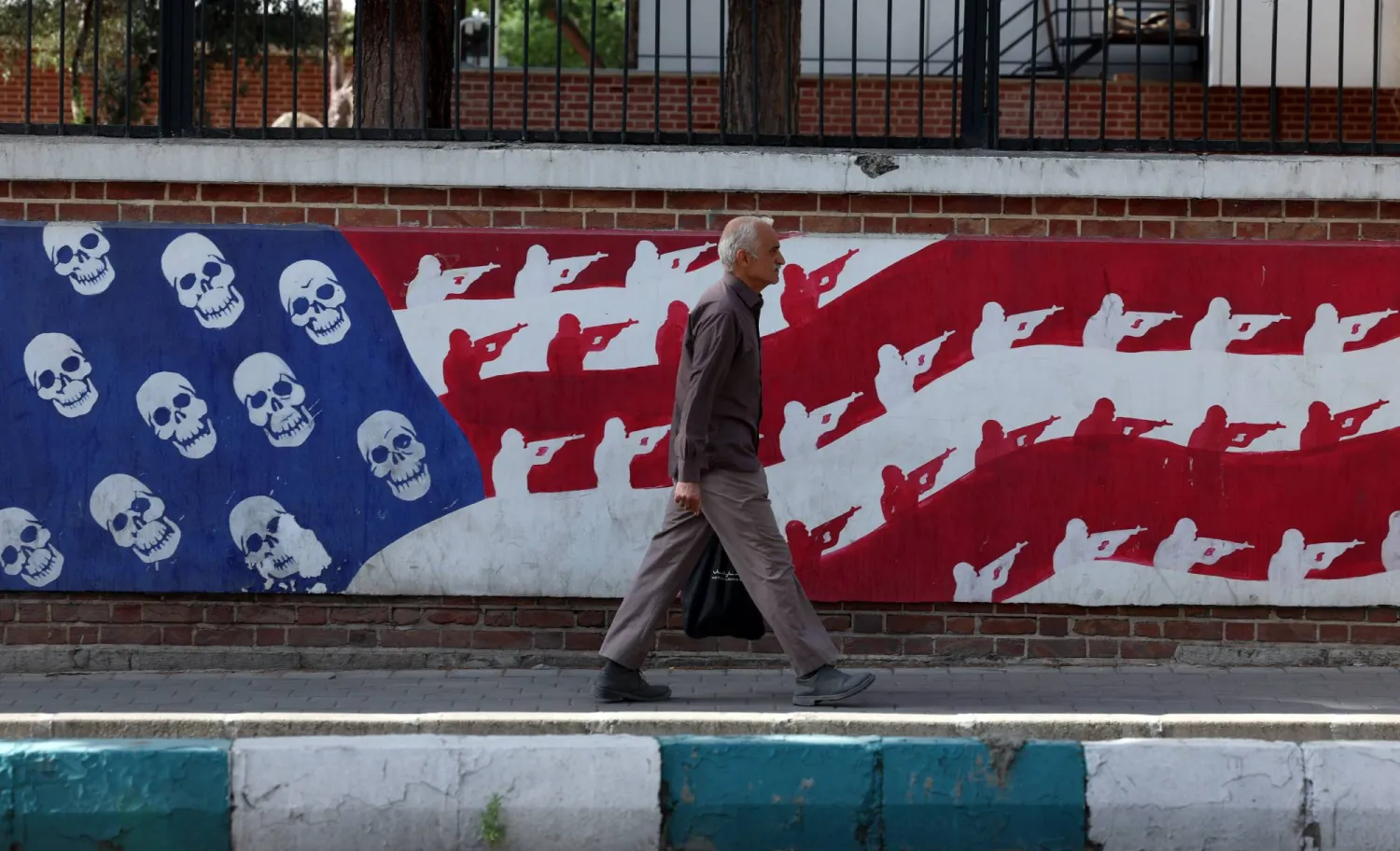 إيراني يمر بجوار جدارية مناهضة للولايات المتحدة في أحد شوارع طهران (إ.ب.أ)