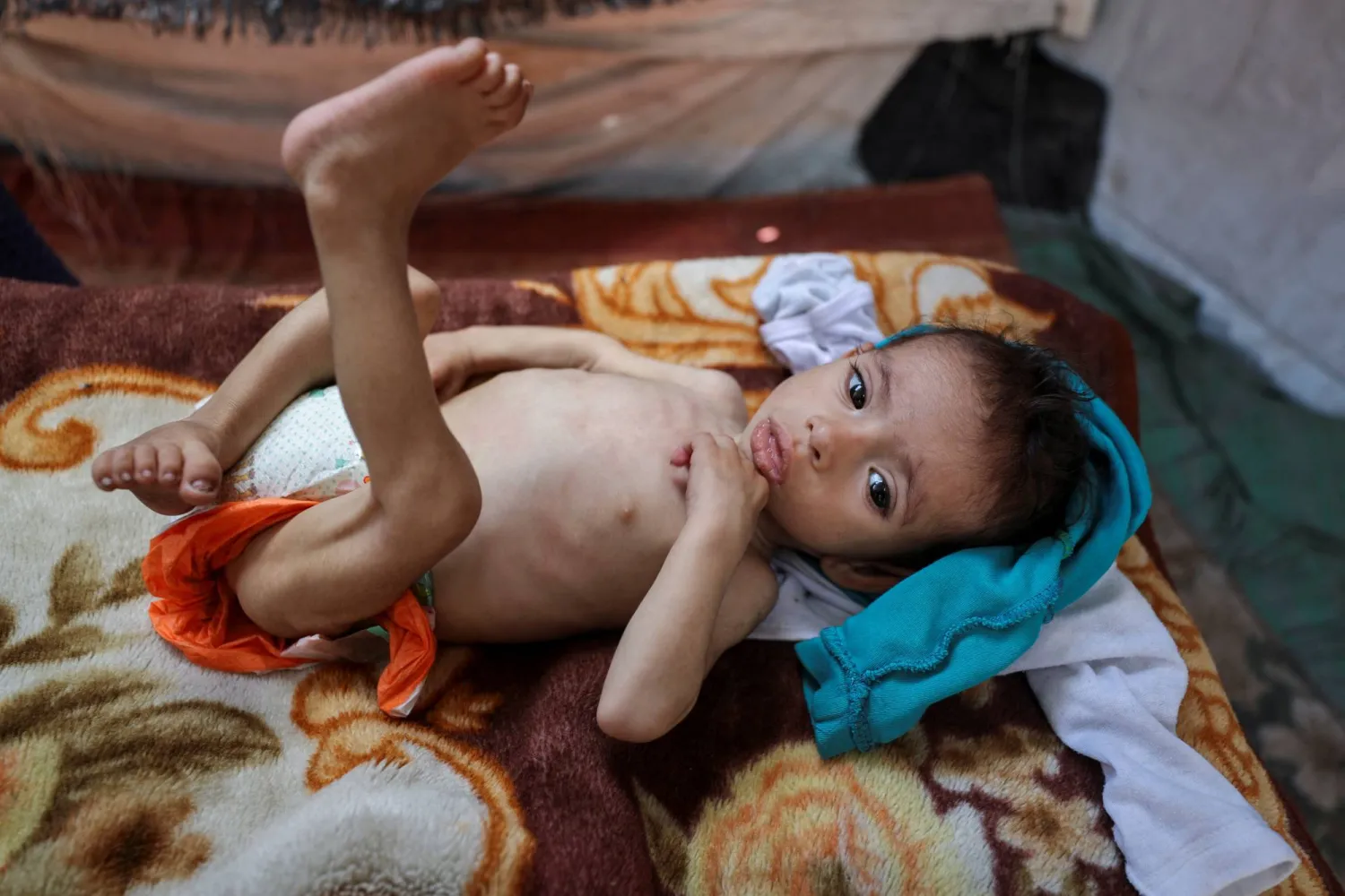 الطفل الفلسطيني زكريا يجلس في خيمة بعد نزوح عائلته نتيجة العمليات العسكرية الإسرائيلية (رويترز)