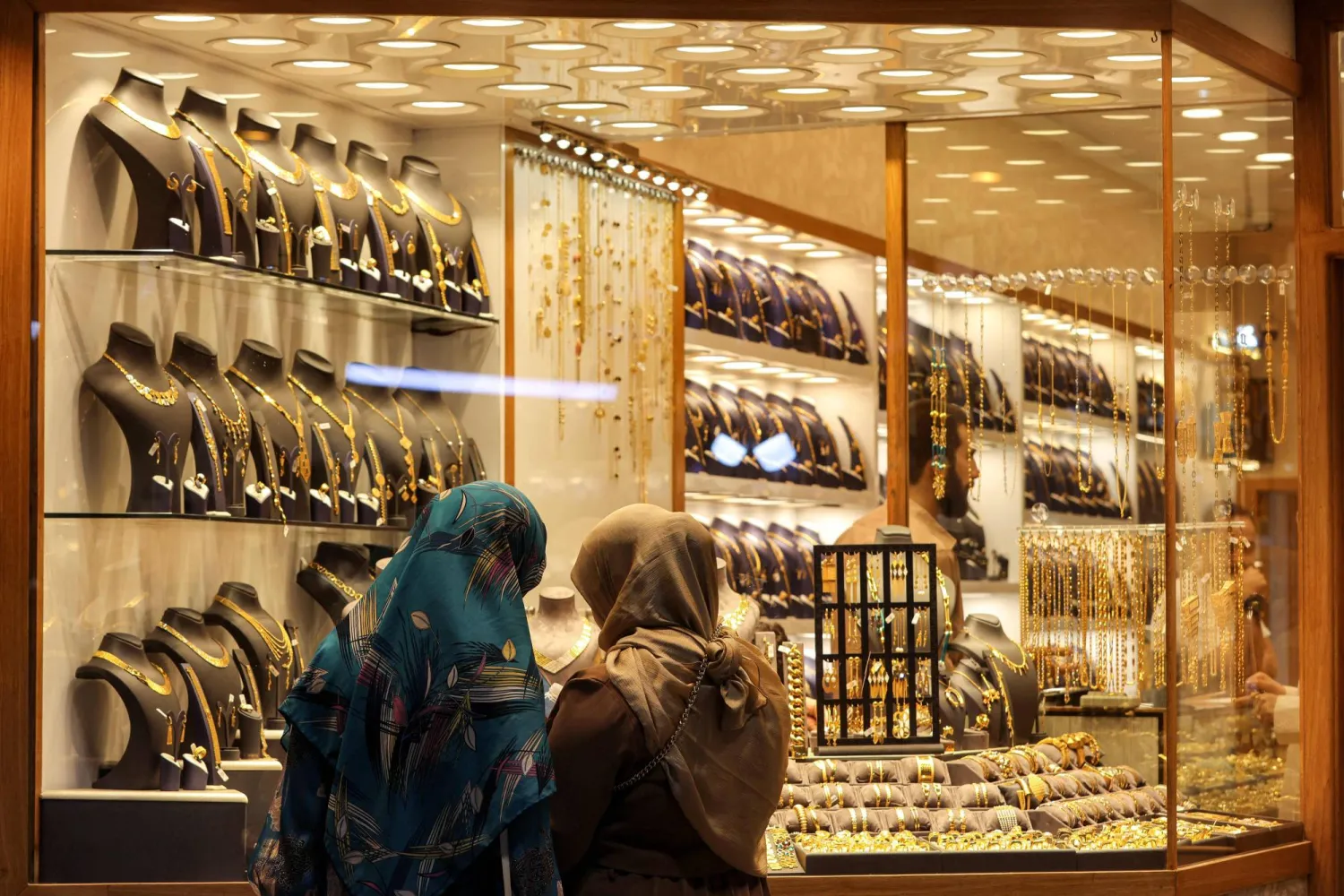 امرأتان تتصفحان المجوهرات خارج نافذة محل صائغ في حي الكرادة ببغداد (أ.ف.ب)