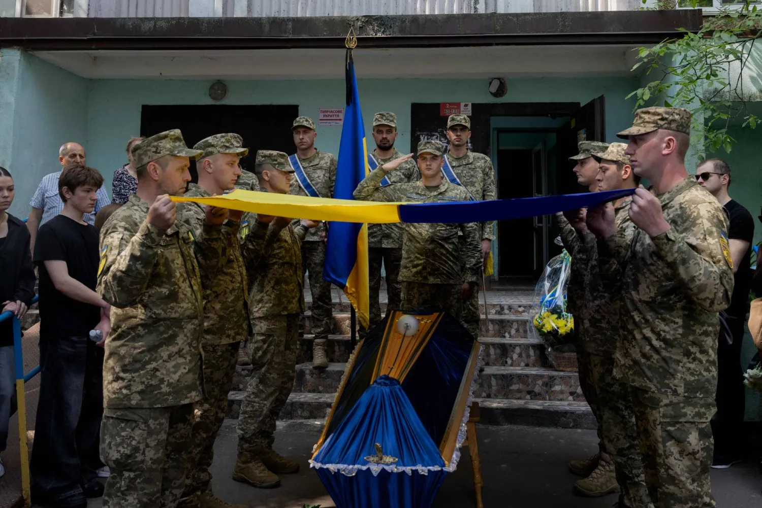 جنود أوكرانيون يرفعون العلم الوطني فوق نعش جندي يبلغ من العمر 21 عاماً (أ.ف.ب)