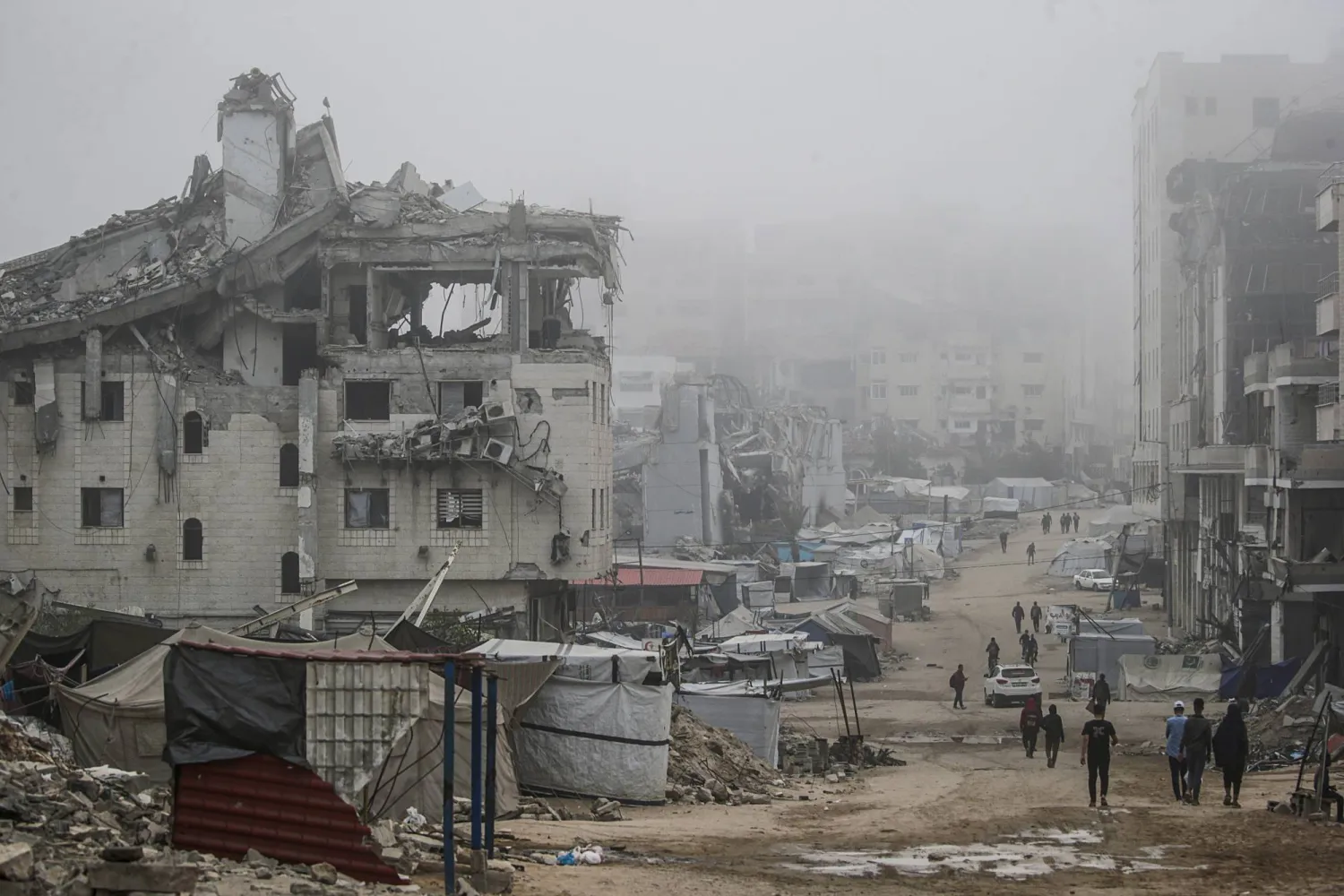 فلسطينيون نازحون داخلياً يتجولون في شوارع مدينة غزة خلال عيد الأضحى المبارك (إ.ب.أ)