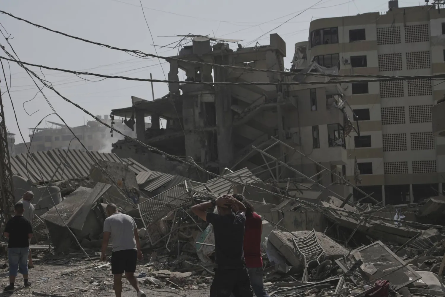 لبنانيون يتفقدون الدمار الناتج من قصف إسرائيلي استهدف الضاحية الجنوبية ليل الخميس (أ.ب)