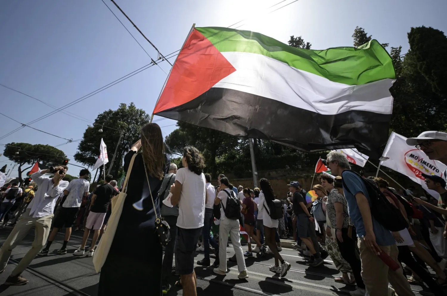 مشاركون في مظاهرة سلمية مؤيدة للفلسطينيين في روما يرفعون العلم الفلسطيني (إ.ب.أ)