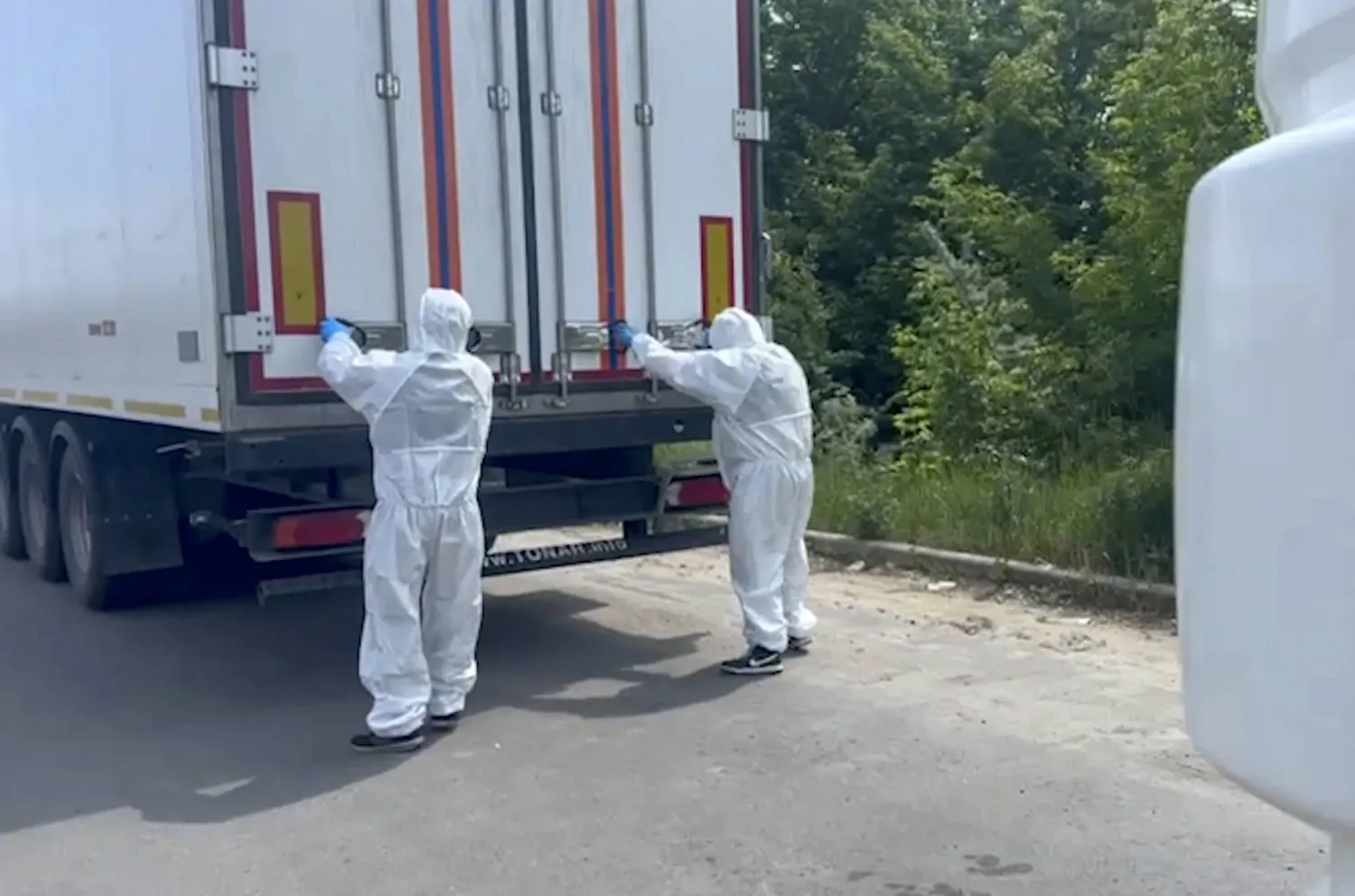 صورة مقتبسة من فيديو وزعته وزارة الدفاع الروسية يظهر رجلين يفتحان شاحنة ضمن قافلة تحمل 1212 من جثامين الجنود الأوكرانيين القتلى في منطقة التبادل الحدودية بين البلدين في وقت سابق هذا الشهر (إ.ب.أ)