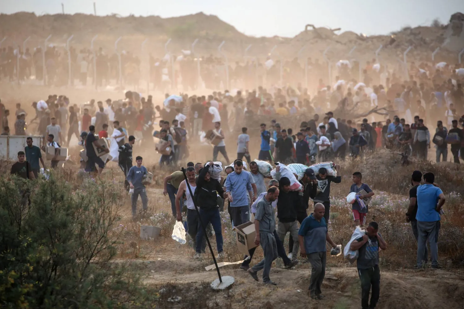 فلسطينيون يحملون إمدادات غذاء وزعتها «مؤسسة غزة الإنسانية» اليوم (أ.ف.ب)