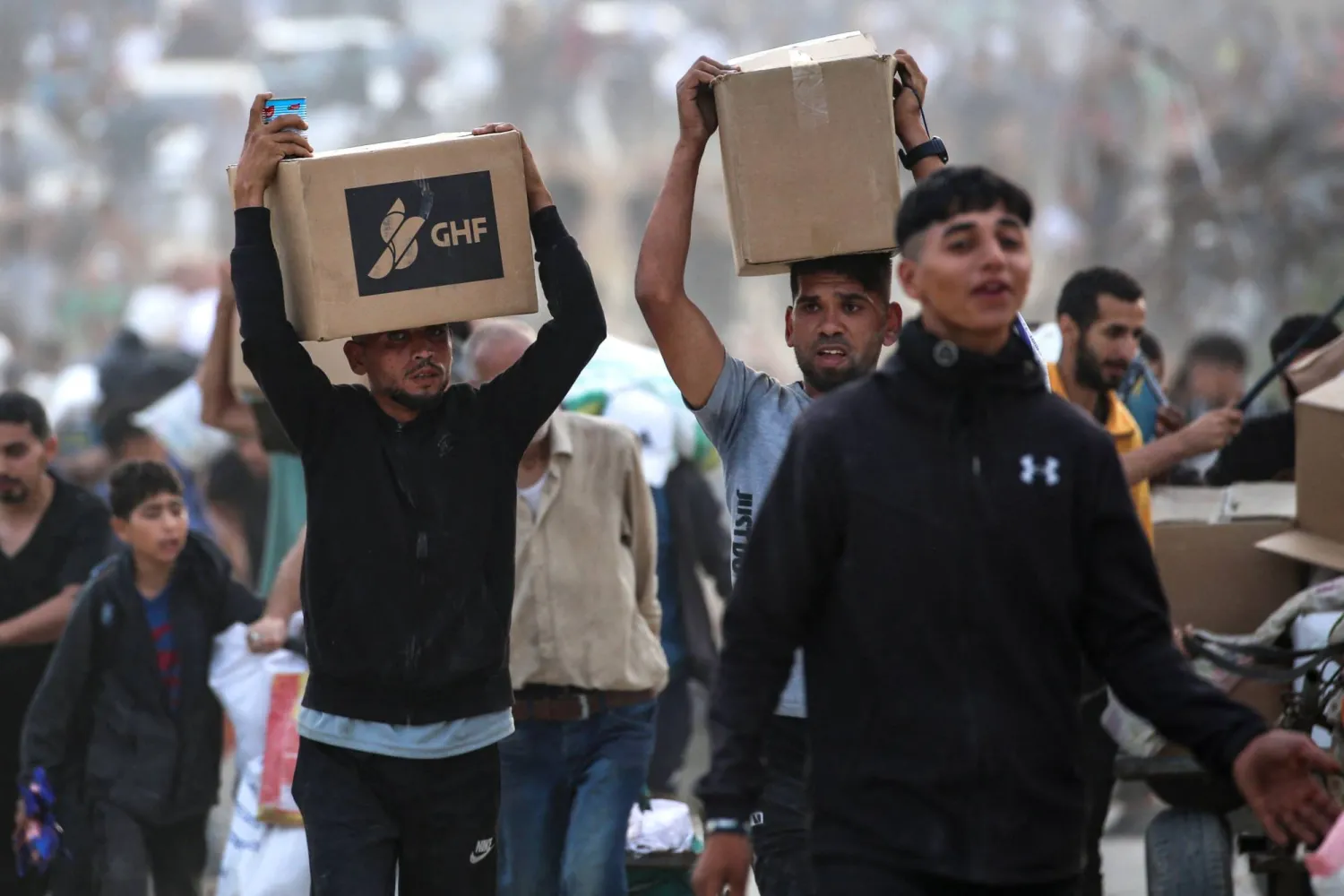 فلسطينيون يحملون معونات حصلوا عليها من «مؤسسة غزة الإنسانية» (أ.ف.ب)