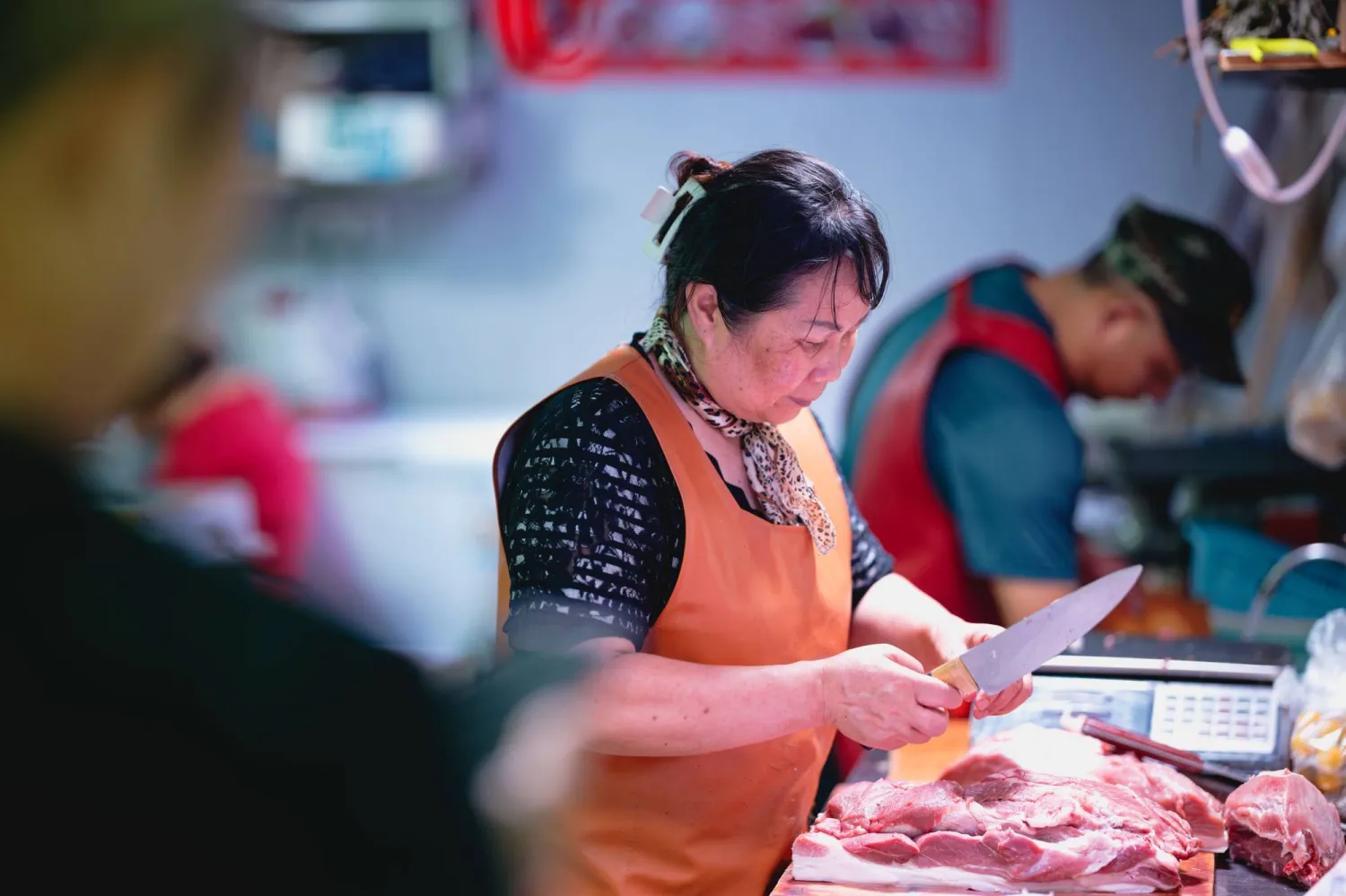 سيدة تقوم بتقطيع اللحم في أحد المتاجر بمدينة شنغهاي الصينية (إ.ب.أ)