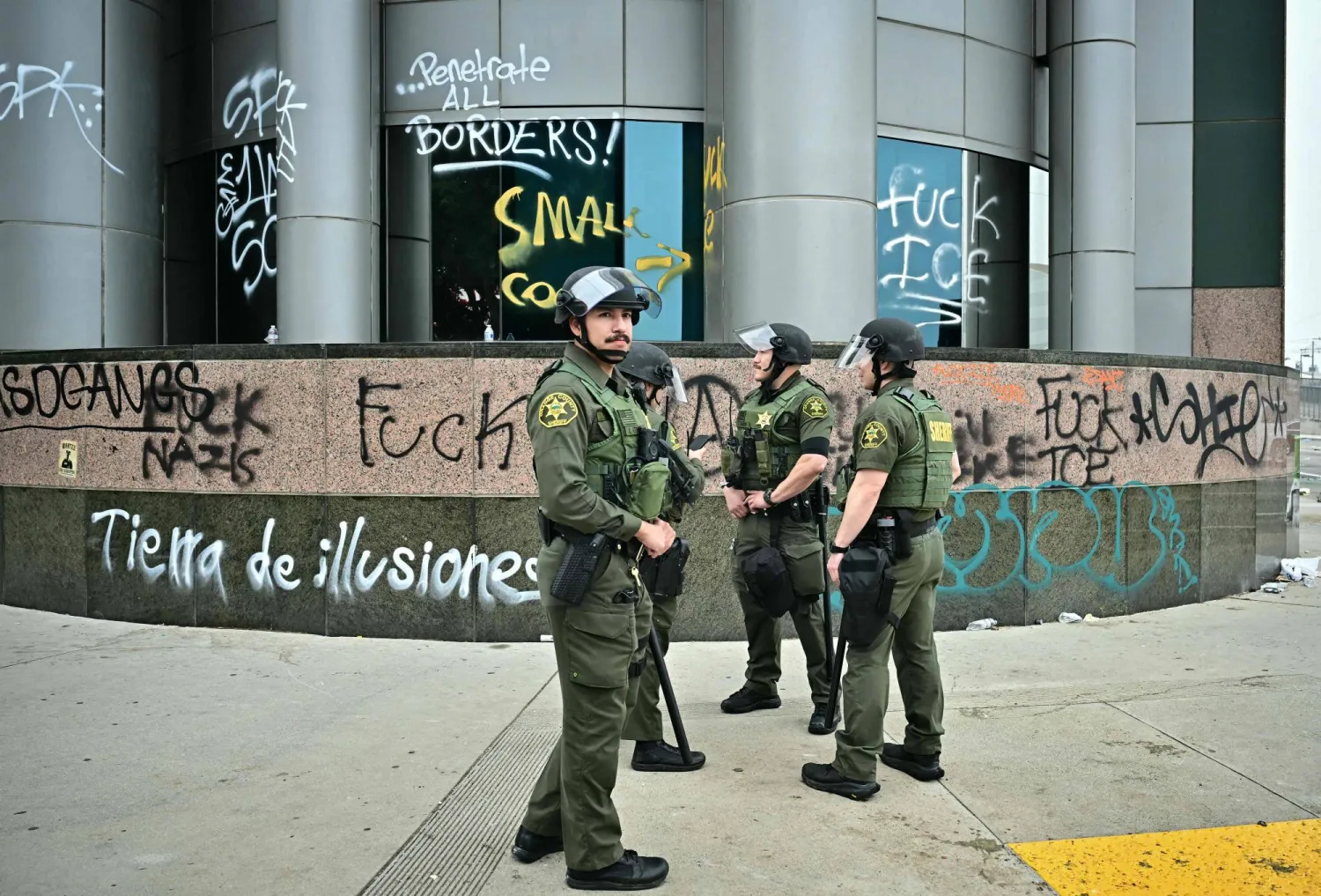 ضباط من شرطة مقاطعة أورانج قرب مبنى طاله الشغب الاثنين غداة الاحتجاجات على عمليات الهجرة في لوس أنجليس (أ.ف.ب)