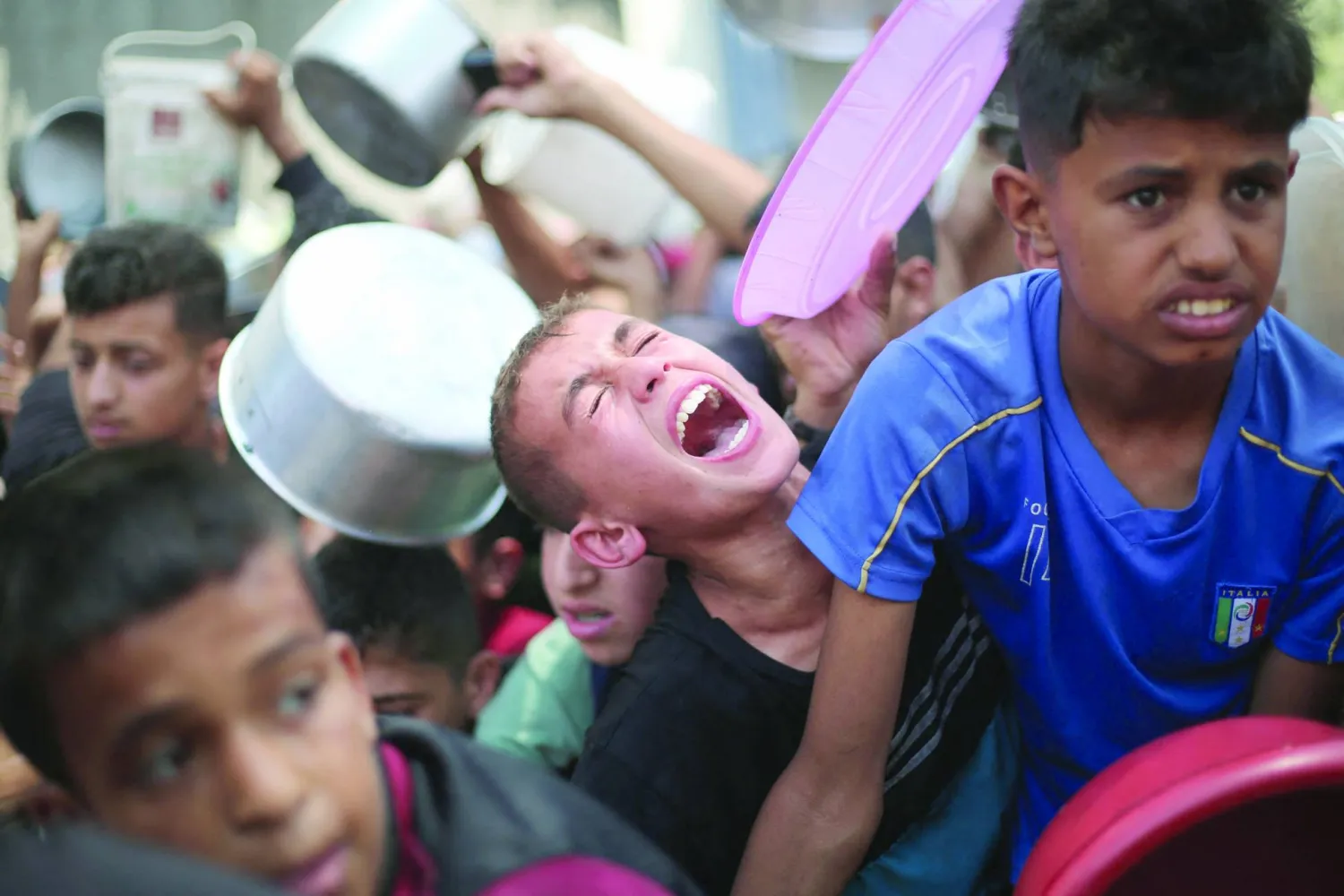 
فلسطينيون ينتظرون الطعام عند نقطة توزيع في النصيرات وسط قطاع غزة أمس (أ.ف.ب)