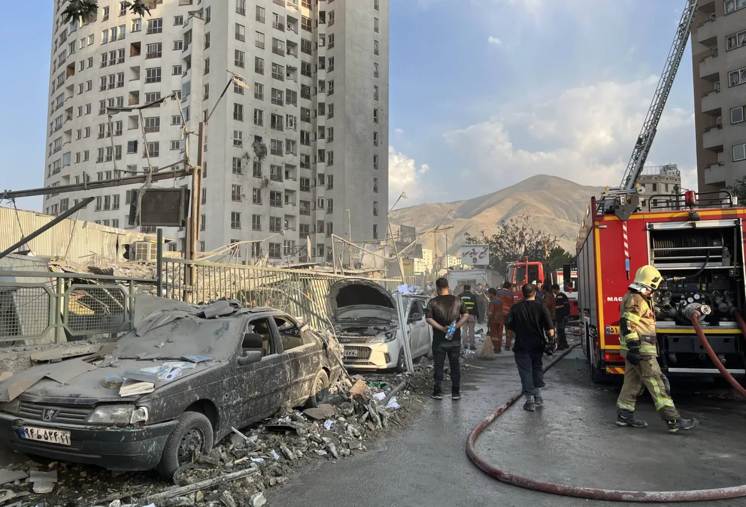 رجال إطفاء يعملون في موقع انفجار في مجمع سكني شمال طهران جراء ضربات إسرائيلية (إ.ب.أ)
