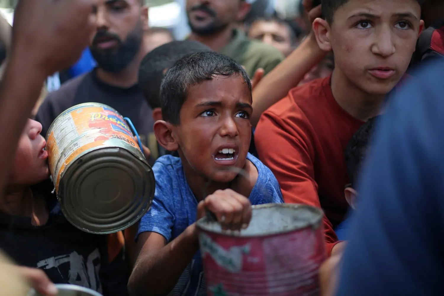 أطفال فلسطينيون ينتظرون الطعام عند نقطة توزيع في النصيرات وسط قطاع غزة (أ.ف.ب)