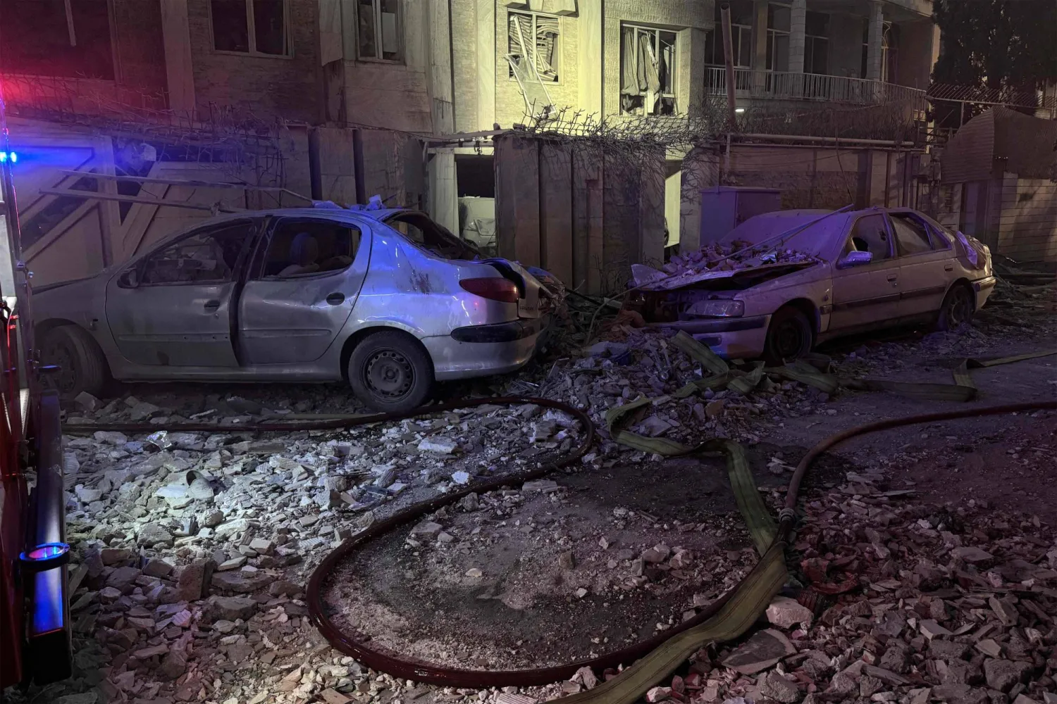 مركبات مدمرة خارج مبنى تعرّض لغارة إسرائيلية في طهران (أ.ف.ب)