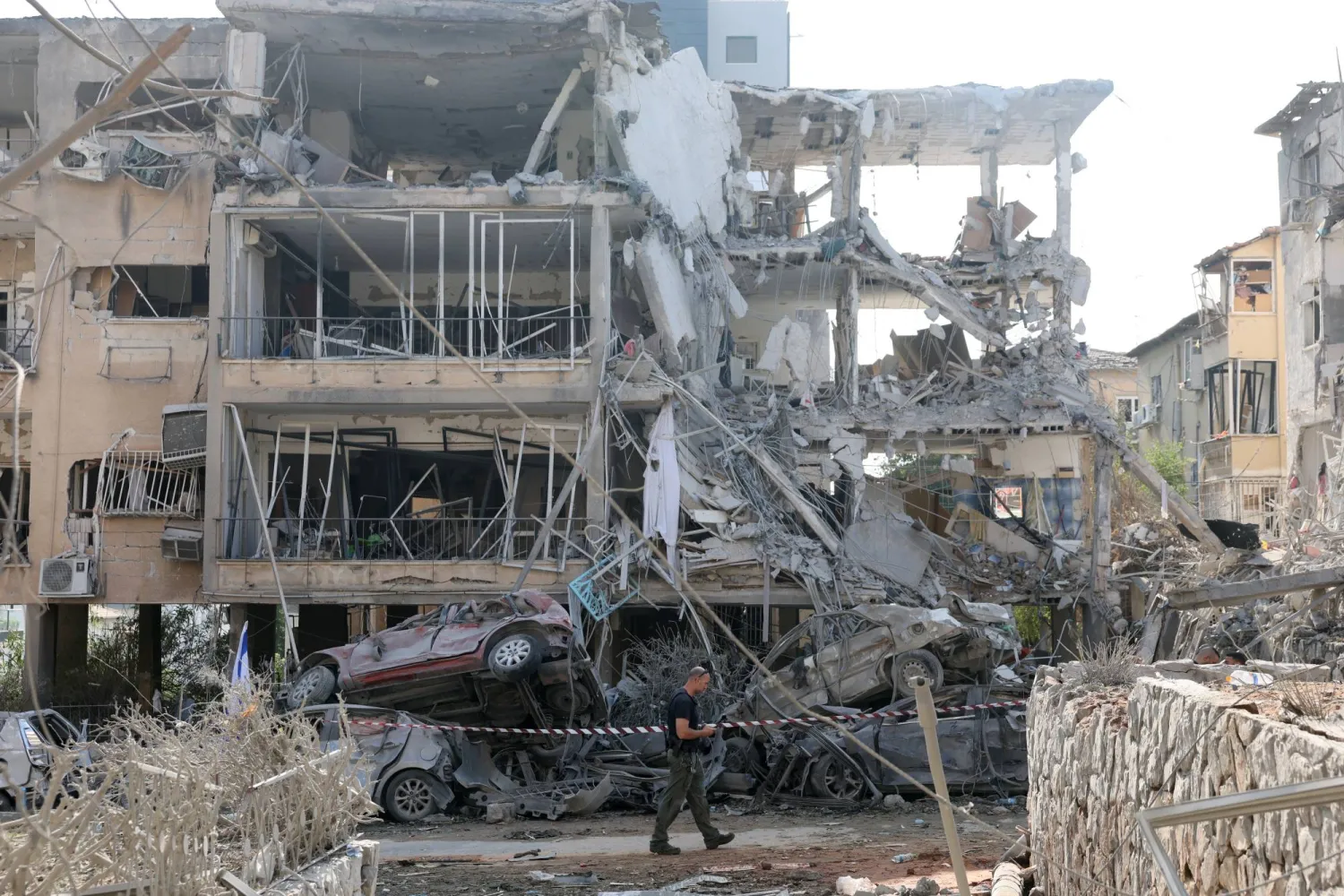 شرطي إسرائيلي يتفقد مبنى سكنياً متضرراً بعد هجوم صاروخي باليستي بالقرب من تل أبيب (إ.ب.أ)