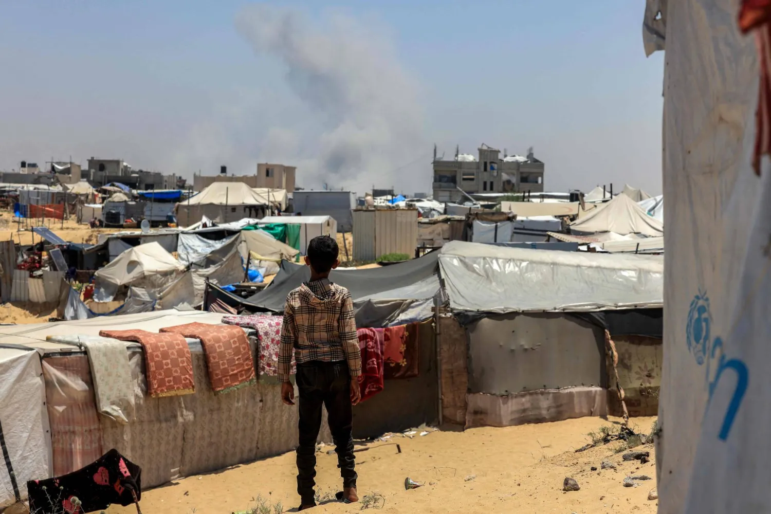 طفل فلسطيني ينظر إلى الدخان المتصاعد في المسافة أثناء القصف الإسرائيلي برفح (أ.ف.ب)
