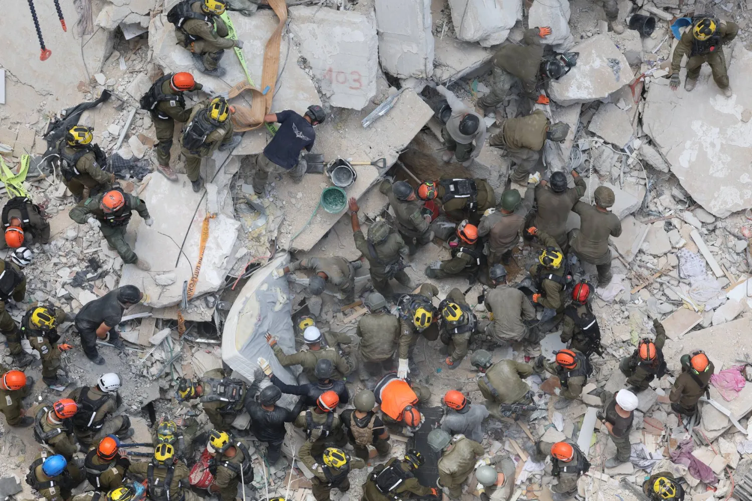 رجال الإسعاف والإنقاذ يبحثون عن ناجين تحت أنقاض مبنى سكني منهار جزئياً بعد سقوط صواريخ باليستية إيرانية على بات يام وسط إسرائيل (إ.ب.أ)