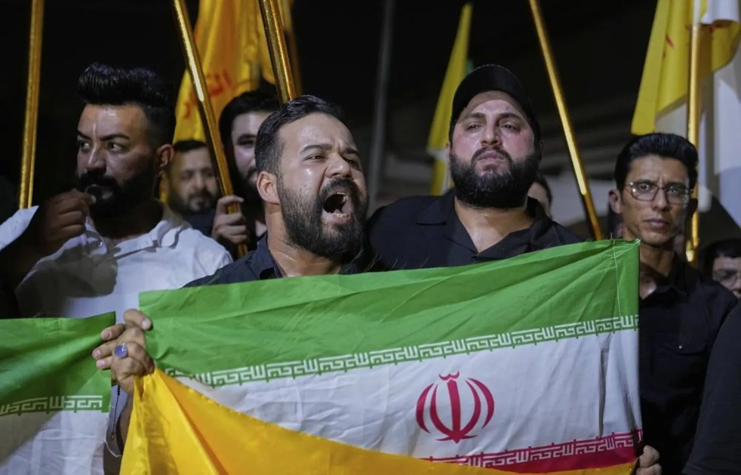 متظاهرون مؤيدون لإيران يحملون علمها قريباً من السفارة الأميركية لدى العراق (أ.ب)