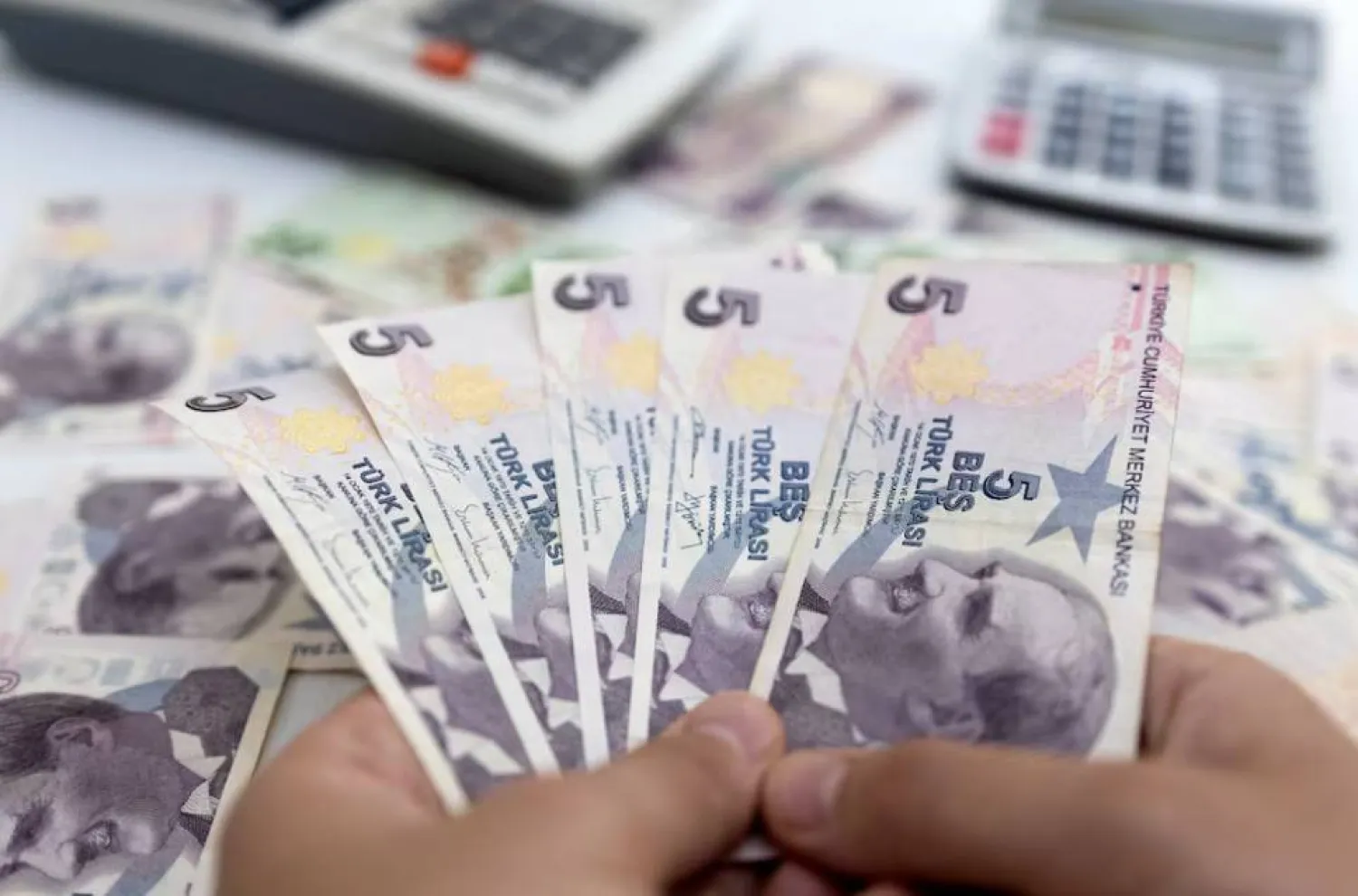 امرأة تمسك أوراقاً نقدية من الليرة التركية (رويترز)