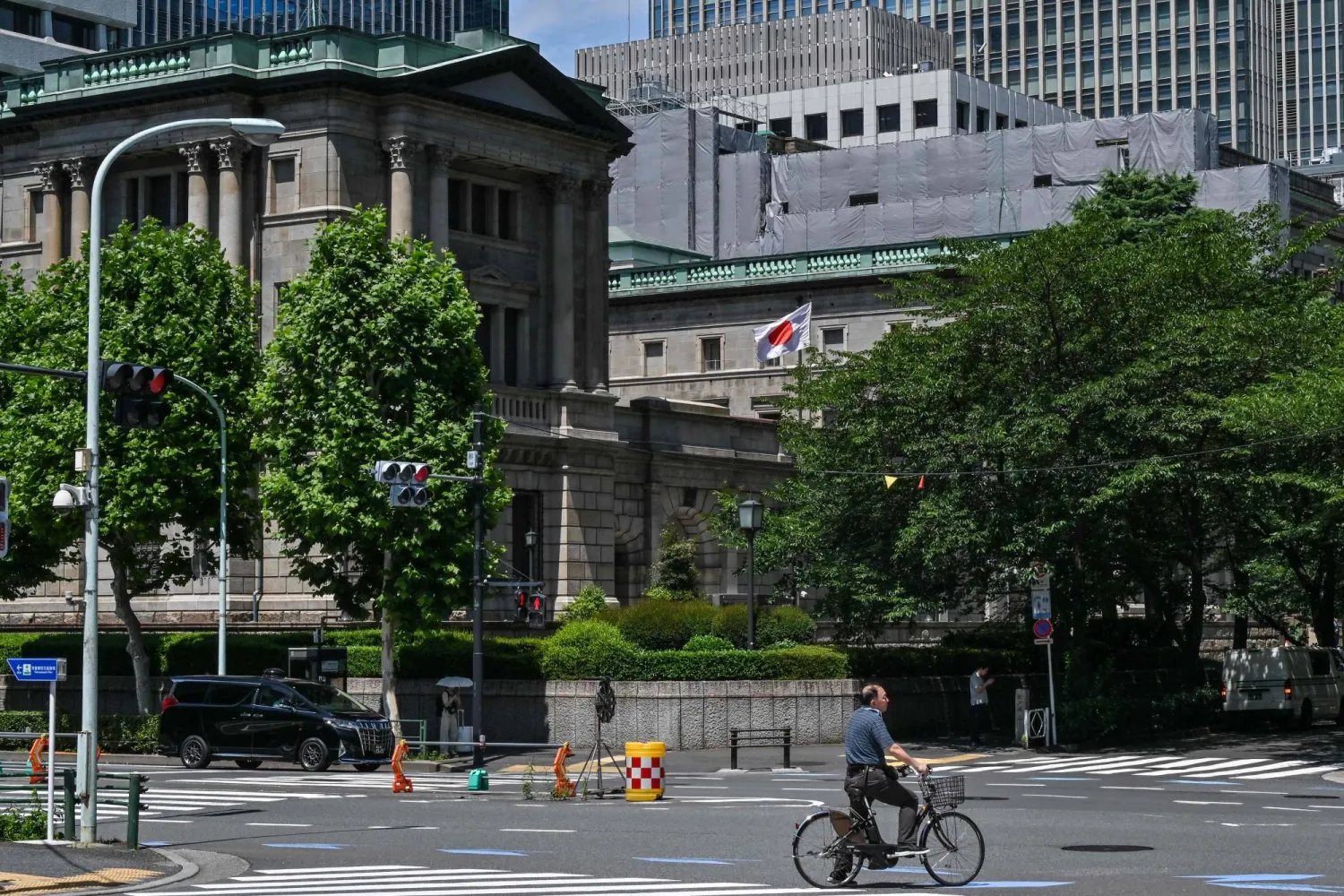رجل على دراجة يمر أمام مقر بنك اليابان المركزي في العاصمة طوكيو (أ.ف.ب)