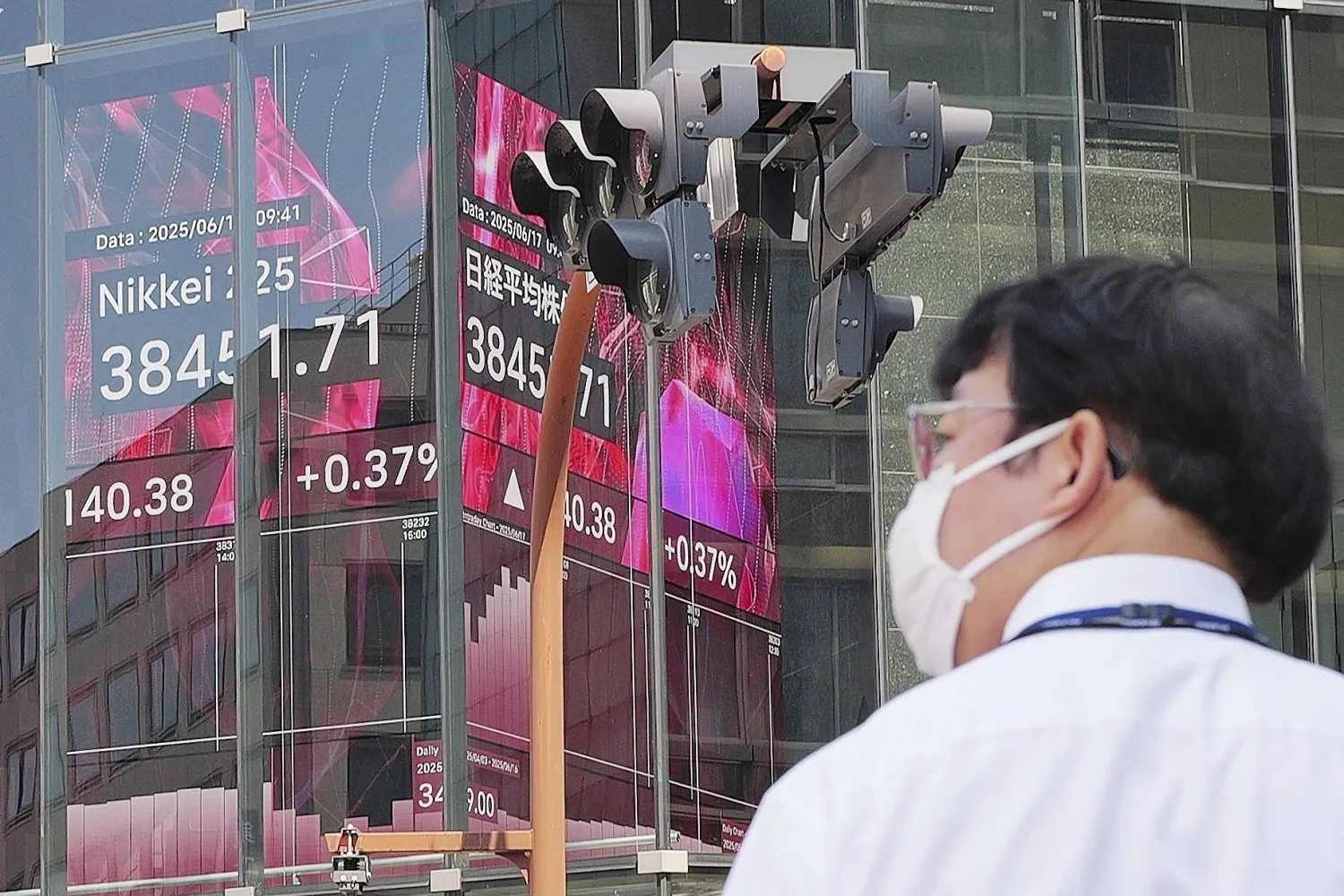 شخص يمرّ أمام لوحة إلكترونية تعرض مؤشر «نيكي» الياباني في طوكيو (أ.ب)