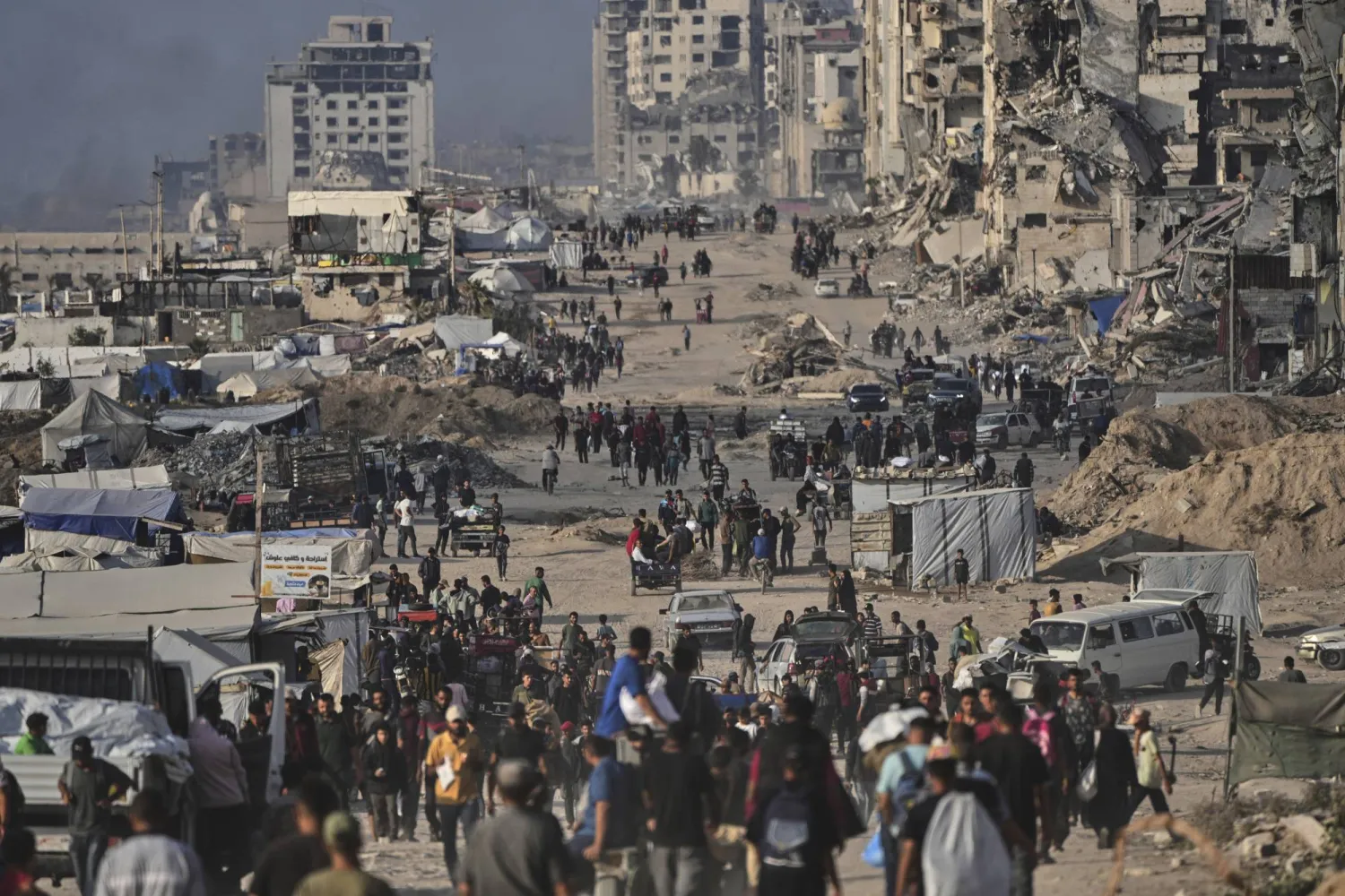 فلسطينيون نازحون يسيرون بين أنقاض المباني المدمرة على طول ساحل مدينة غزة 9 يونيو 2025 (أ.ب)
