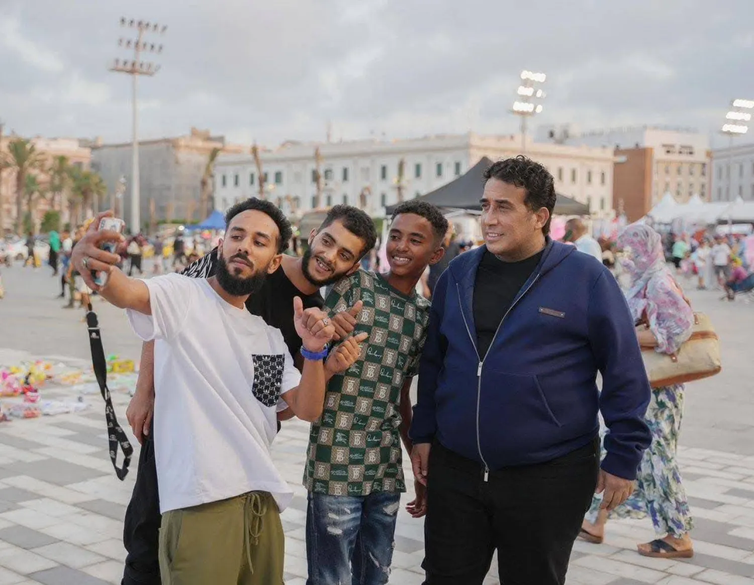 شباب ليبيون يلتقطون صورة تذكارية مع المنفي خلال جولته بشوارع طرابلس (مكتب المنفي)