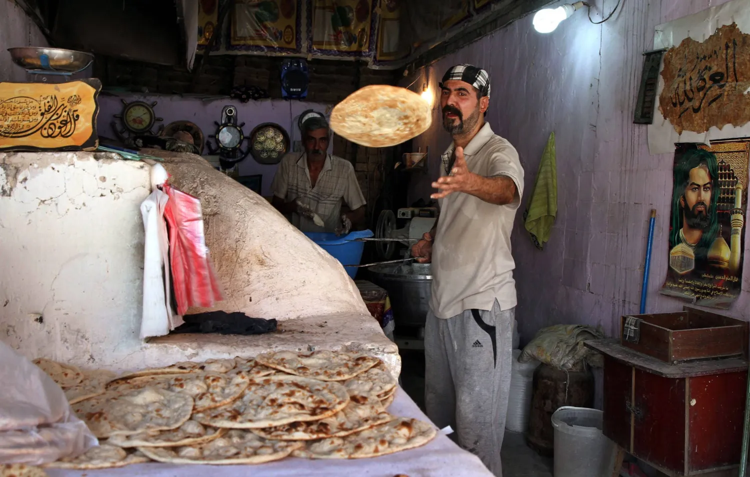 رجل عراقي يخبز خبزاً تقليدياً في أحد أفران بغداد (إ.ب.أ)