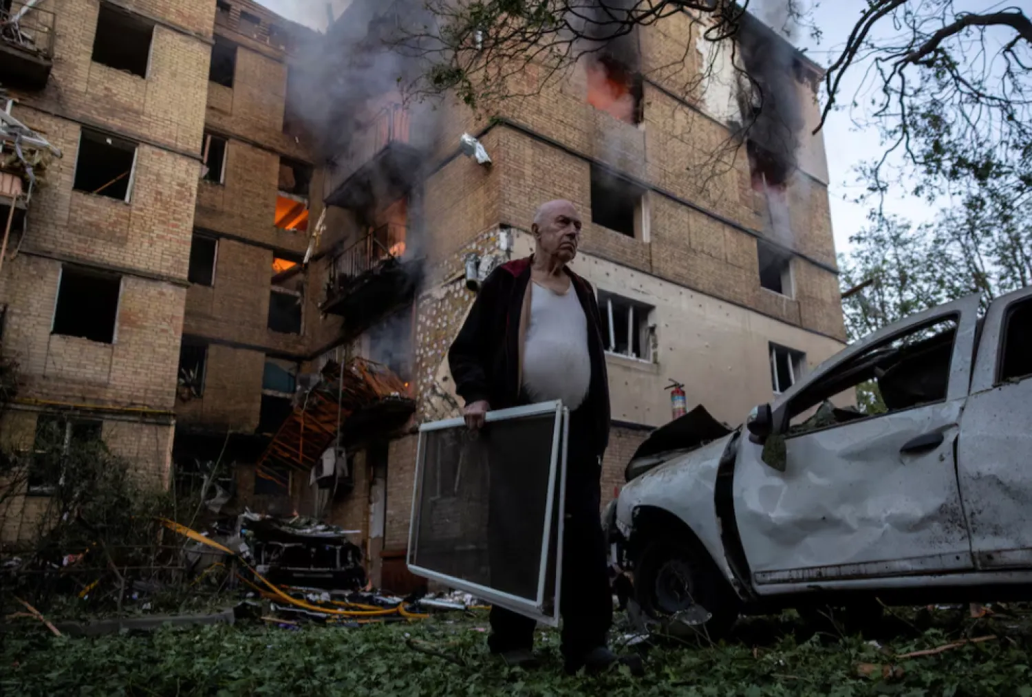 A resident carries window screens outside a damaged apartment building that is on fire after a Russian drone strike, amid Russia's attack on Ukraine, in Kyiv, Ukraine June 17, 2025. REUTERS/Thomas Peter TPX IMAGES OF THE DAY 