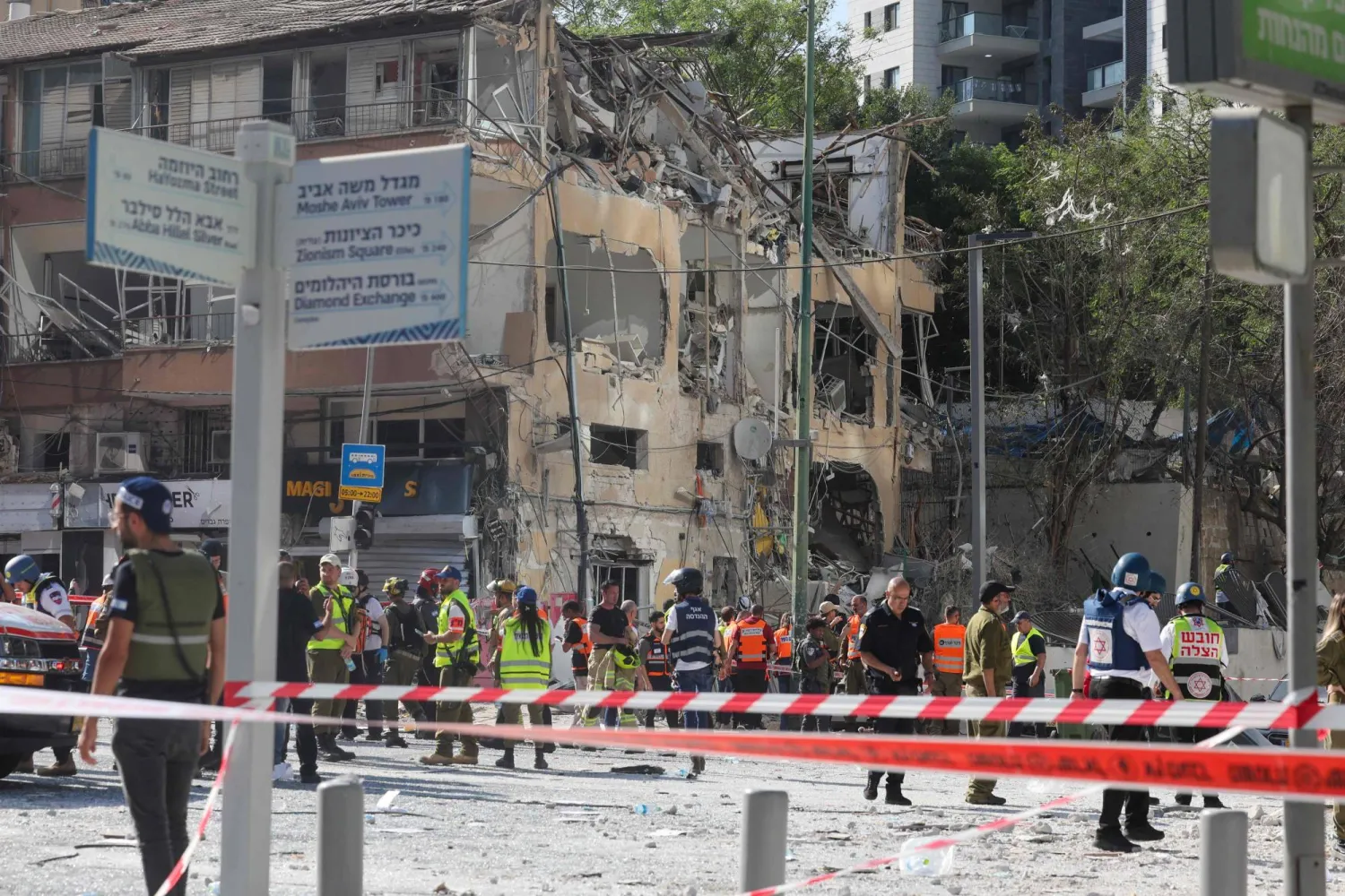 خدمات الطوارئ الإسرائيلية تتفقد المنطقة أمام مبنى متضرر في موقع هجوم صاروخي إيراني في رامات غان وسط إسرائيل (أ.ف.ب)