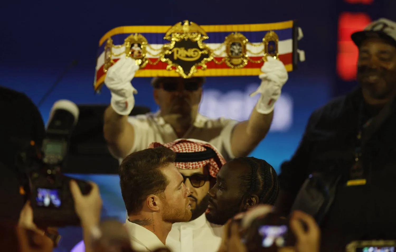 الملاكمان في لقطة تحدٍ أمام الكاميرات وسط متابعة آل الشيخ (رويترز)