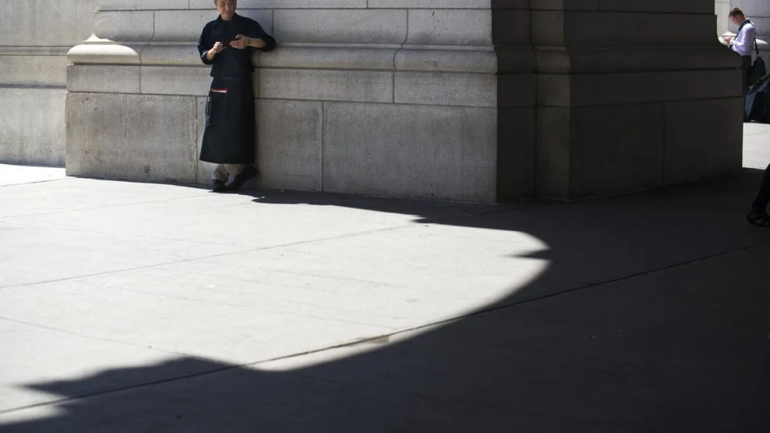 A chef takes a break to check his phone in a sliver of shade outside Union Station on August 12, 2016 in Washington,DC. Gabriella Demczuk / GETTY IMAGES NORTH AMERICA/AFP/File
