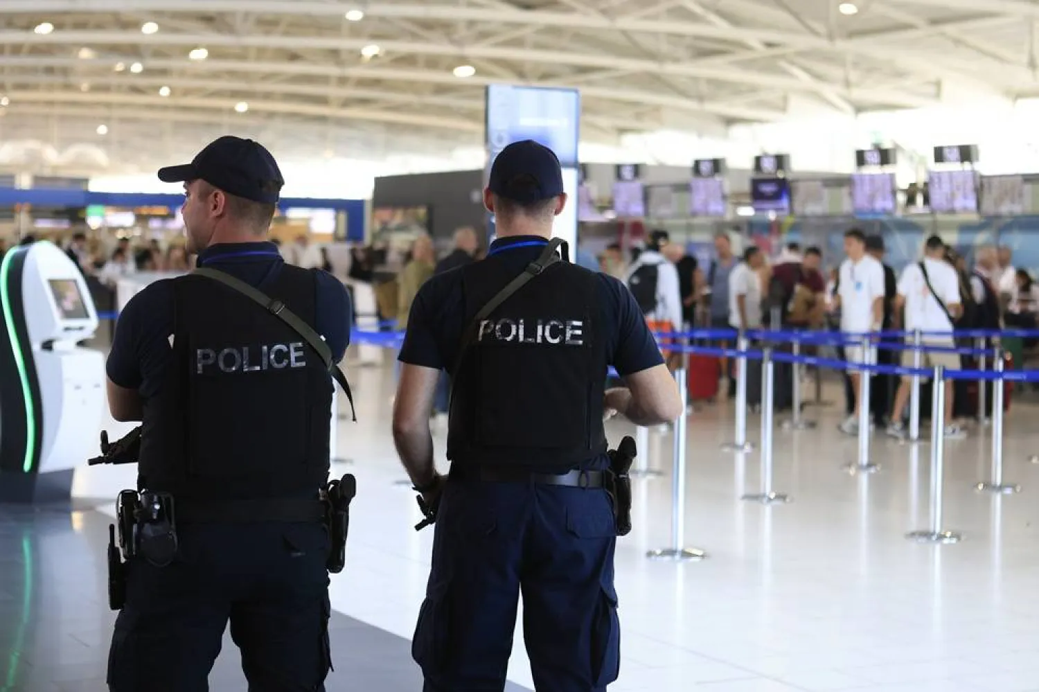 Armed members of Cyprus' police force stand guard as Israeli passengers heading for Israel's port city of Haifa line up to check in at Larnaca International airport in Cyprus, 20 June 2025. (EPA)
