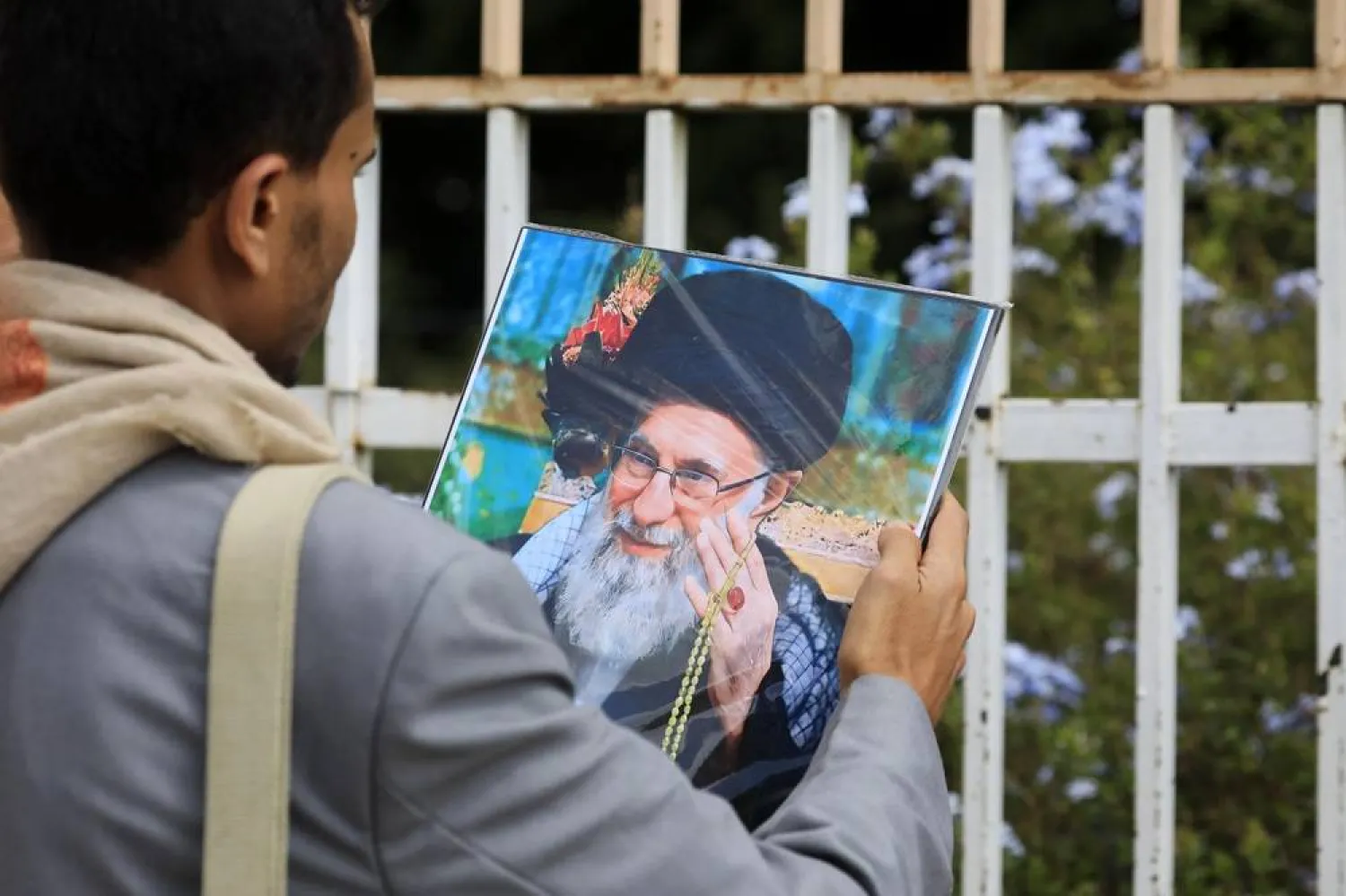 A Houthi supporter holds a portrait of Iran's Supreme Leader Ali Khamenei on a street in Sanaa, Yemen, 20 June 2024. (EPA) 