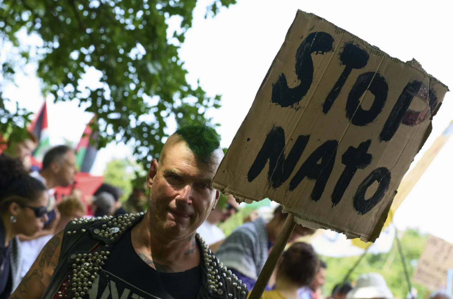 A man holds a placard during a demonstration ahead of the NATO summit in The Hague, Netherlands, Sunday, June 22, 2025. (AP Photo/Peter Dejong)