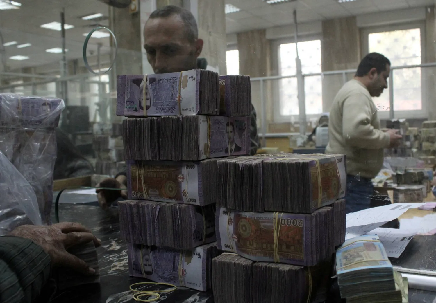FILE PHOTO: Bundles of Syrian currency notes are stacked up as an employee counts money at Syrian central bank, in Damascus,Syria, January 12, 2025. REUTERS/Firas Makdesi/File Photo