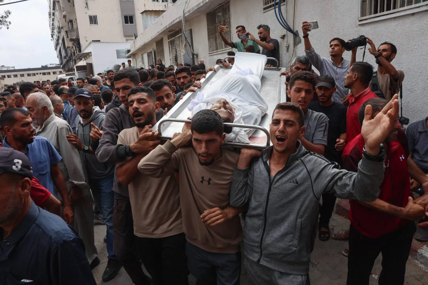 فلسطينيون يحملون جثمان رجل قُتل اليوم في انتظار المساعدات الإنسانية في مدينة غزة (أ.ف.ب)